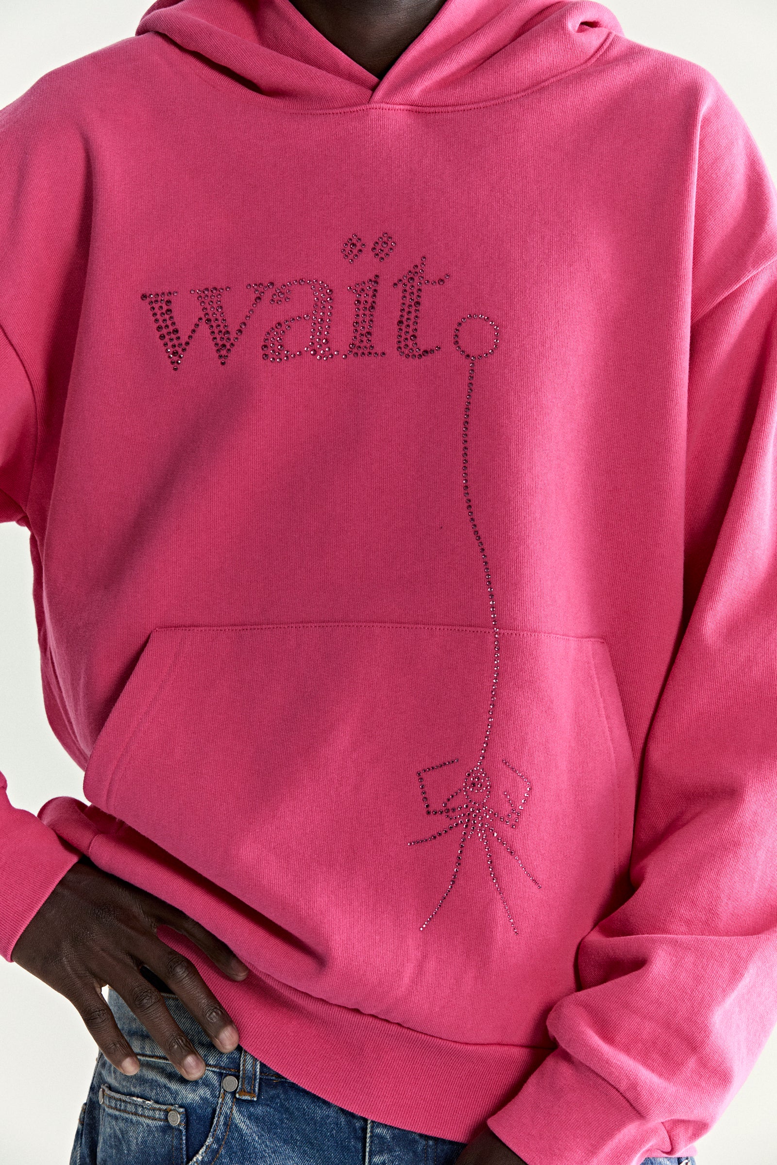 Pink 13oz cotton fleece hoodie with rhinestone "Wait" detail, kangaroo pocket, and rib knit trim.