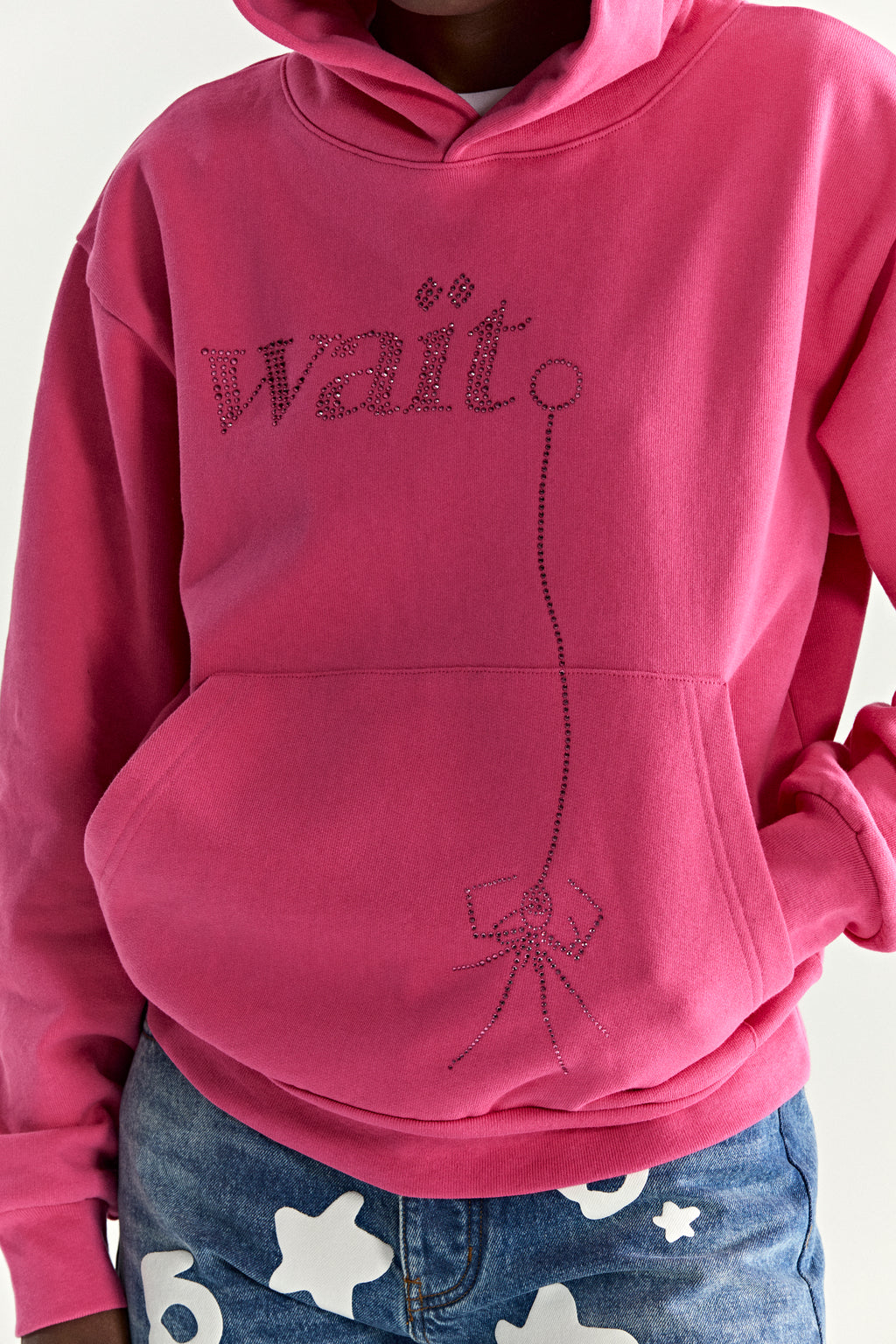 Pink 13oz cotton fleece hoodie with rhinestone "Wait" graphic, kangaroo pocket, and rib knit trim.