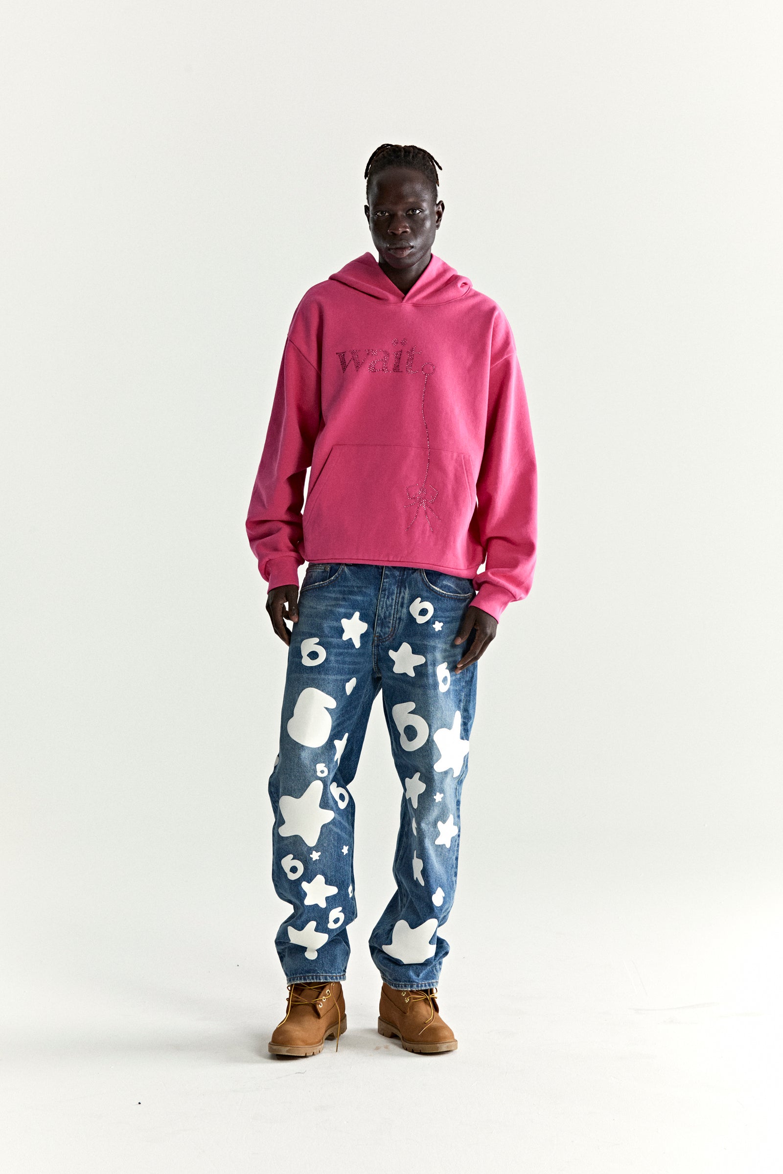 Model in pink WAIT STONE HOODIE with rhinestone detail, kangaroo pocket, and rib knit.