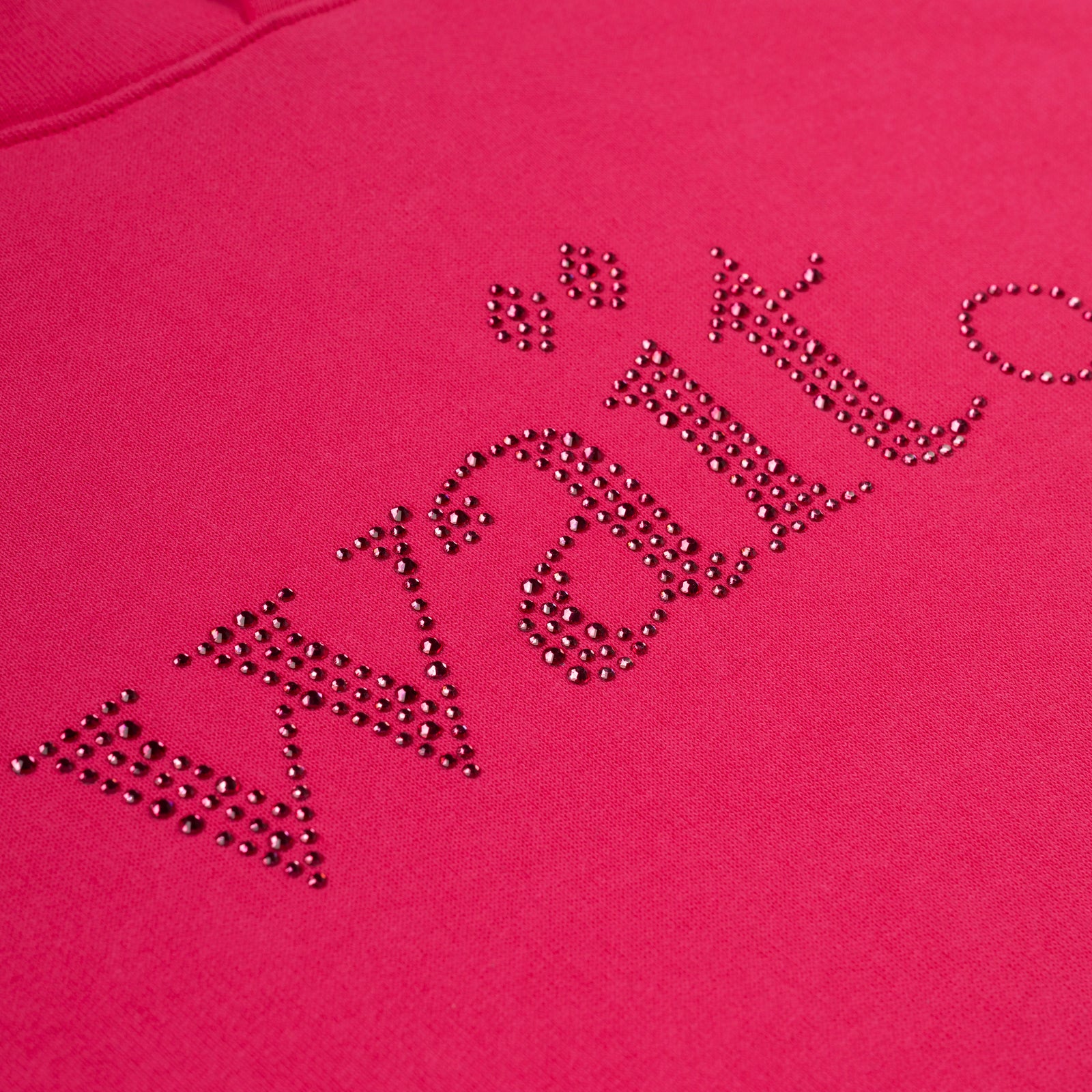 Close-up of a vibrant pink cotton fleece hoodie with "Wait" spelled in sparkling rhinestones.