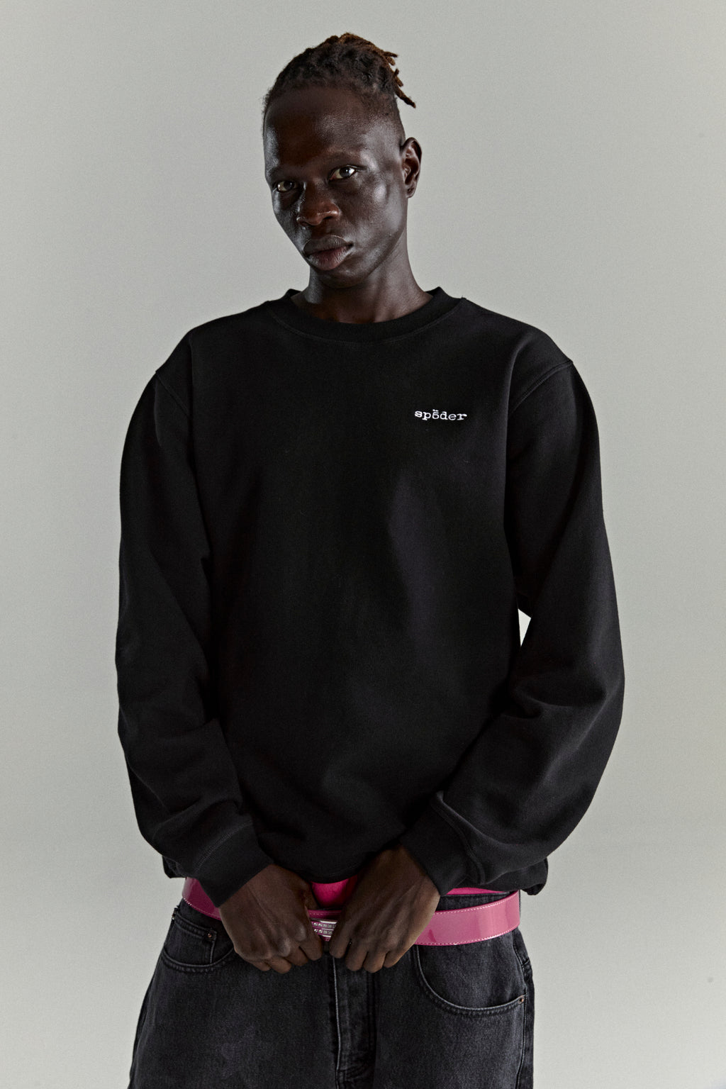 Black CORE CREWNECK sweatshirt with white embroidered 'SP5DER' logo on chest, worn by a model.