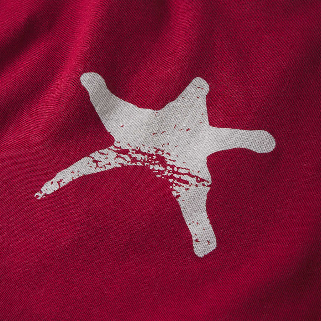 Red 100% cotton long sleeve tee featuring a distressed white star graphic print on the fabric.
