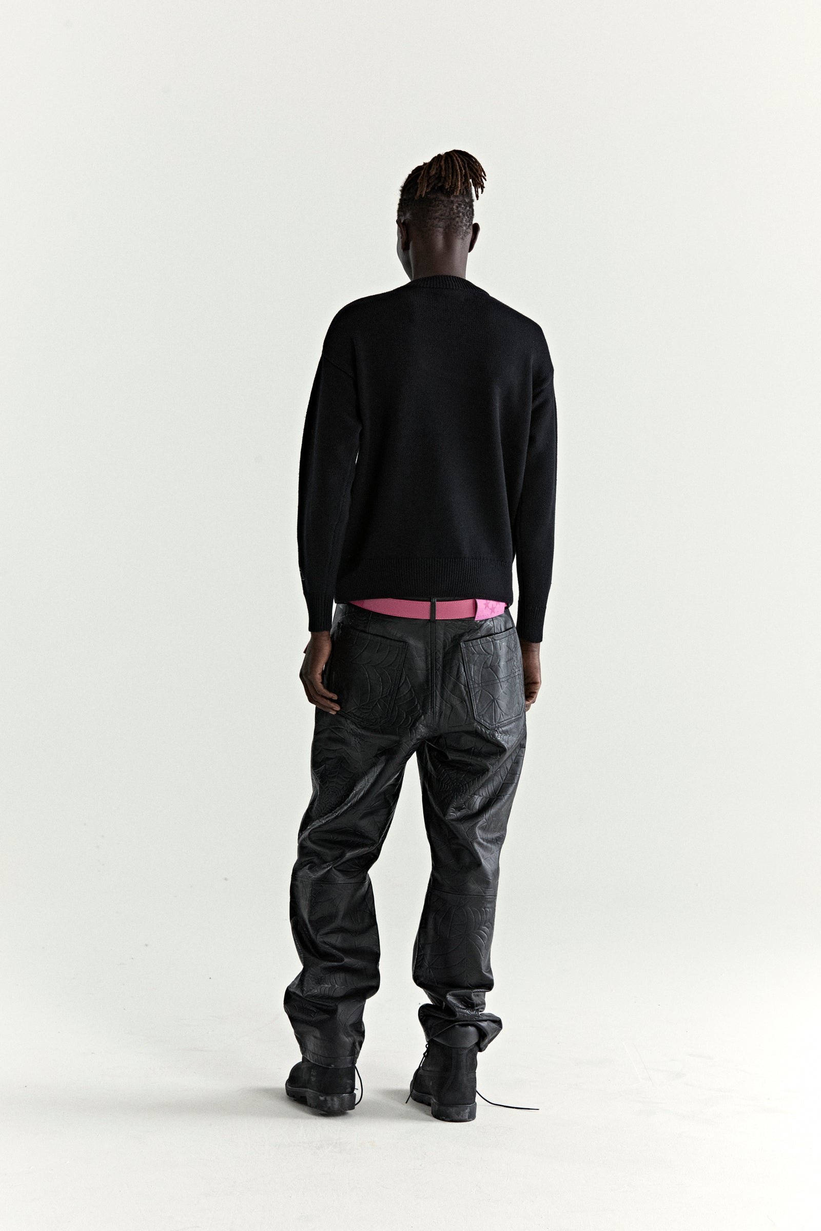 Black knitted sweater with ribbed collar, cuffs, and hem, worn by a person facing away.