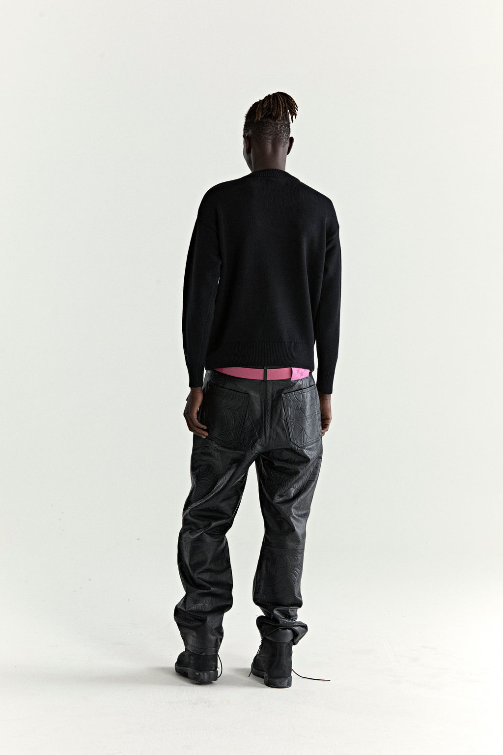 Black knitted sweater with ribbed collar, cuffs, and hem, worn by a person facing away.