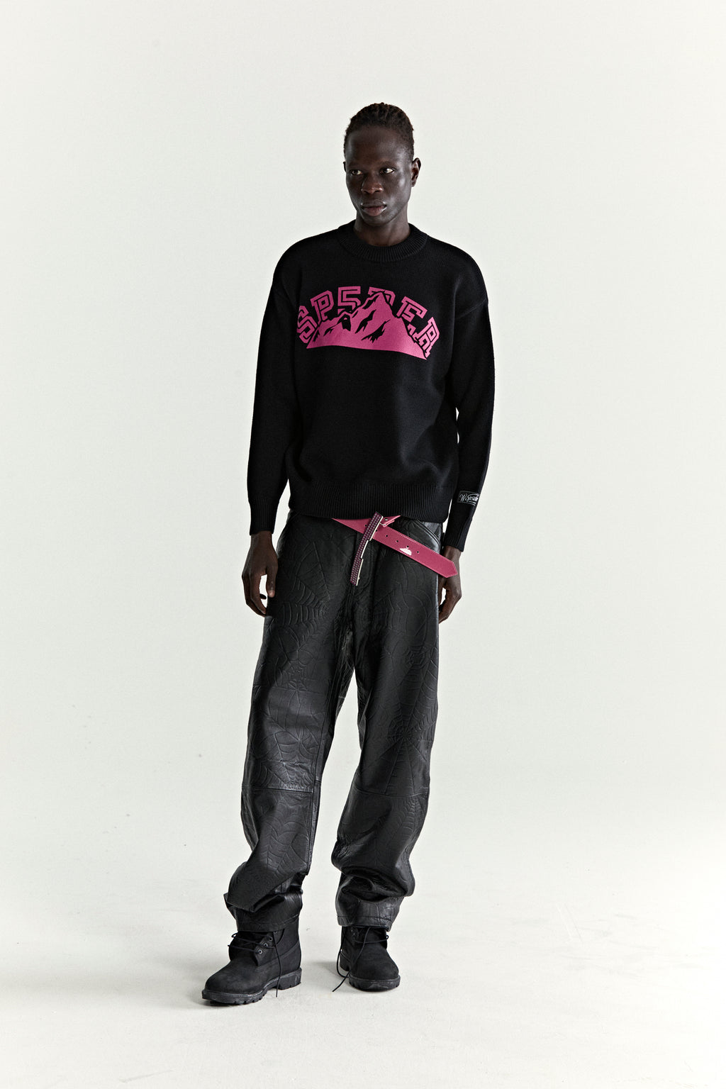 Black knitted MOUNTAIN VALLEY SWEATER with pink SP5DER graphic, ribbed trim, and sleeve patch.