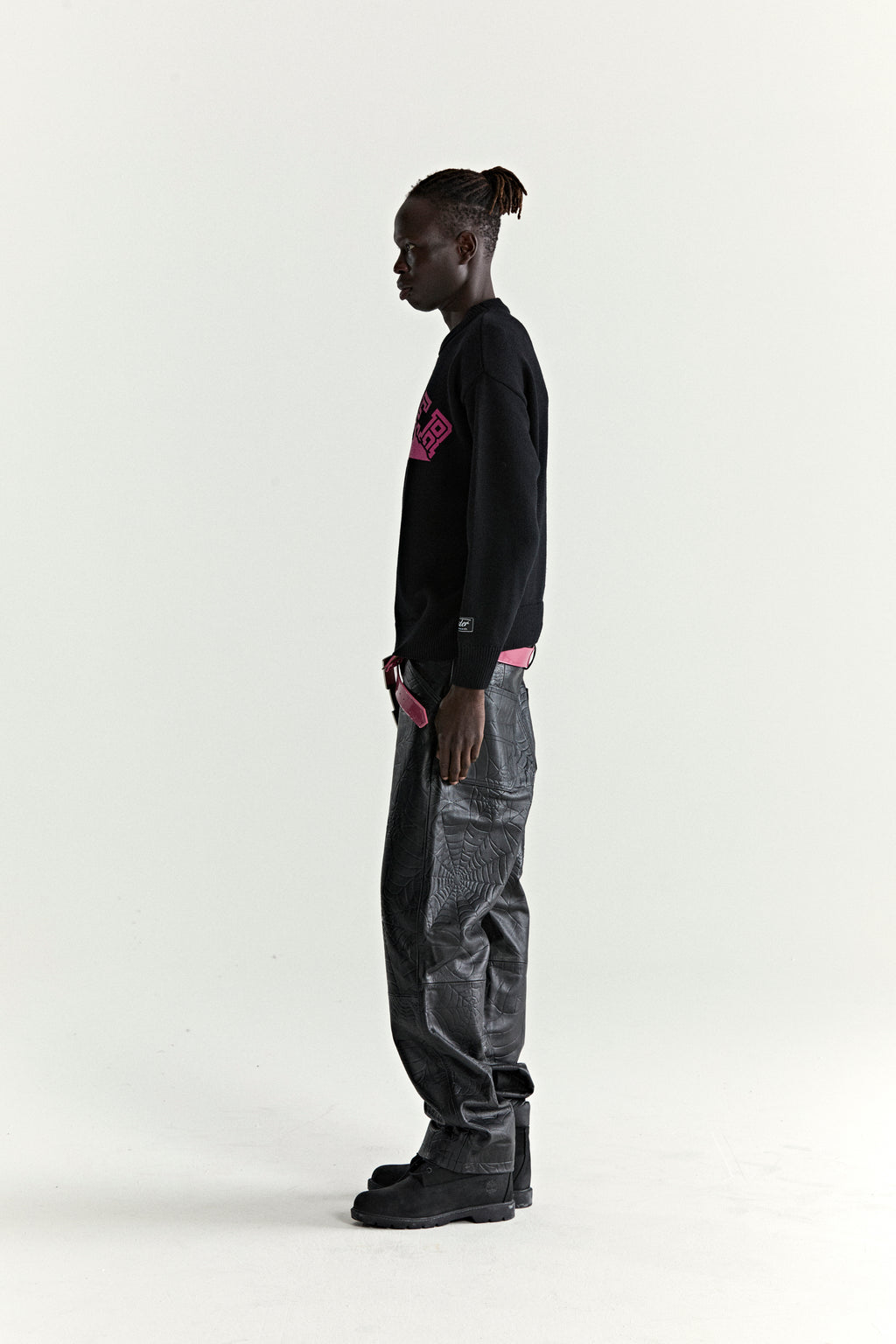 Black knitted sweater with pink Mountain SP5DER graphic, ribbed trim, and sleeve patch.