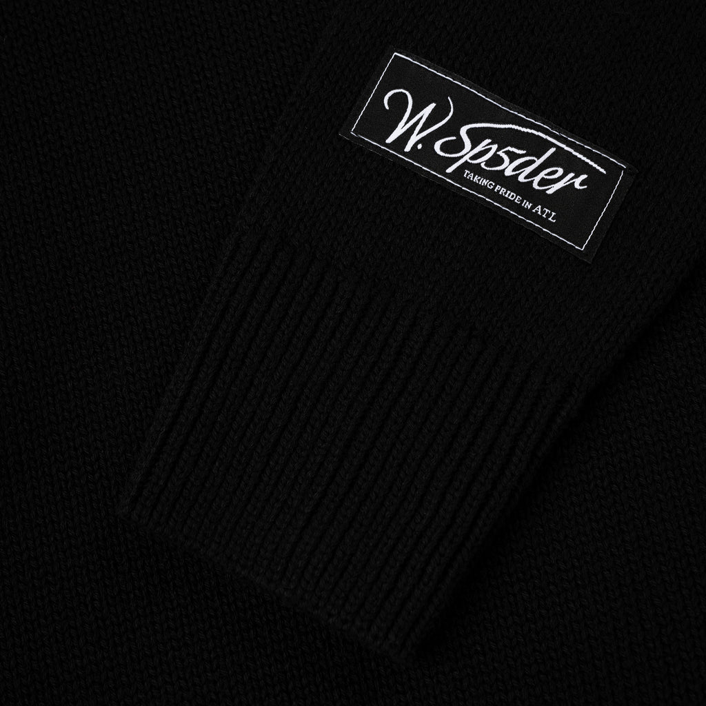 Black knitted sweater with "W. Sp5der Taking Pride in ATL" patch on the sleeve.