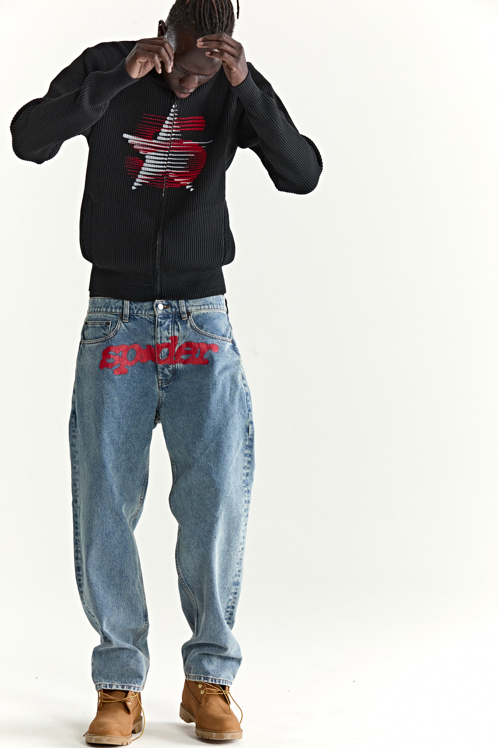 Black ribbed wool/cotton zip sweater with red star graphic, paired with light wash jeans.