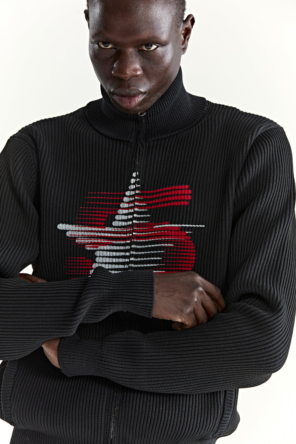 Black rib-knit wool/cotton zip sweater with stand collar and red/white graphic print at chest.