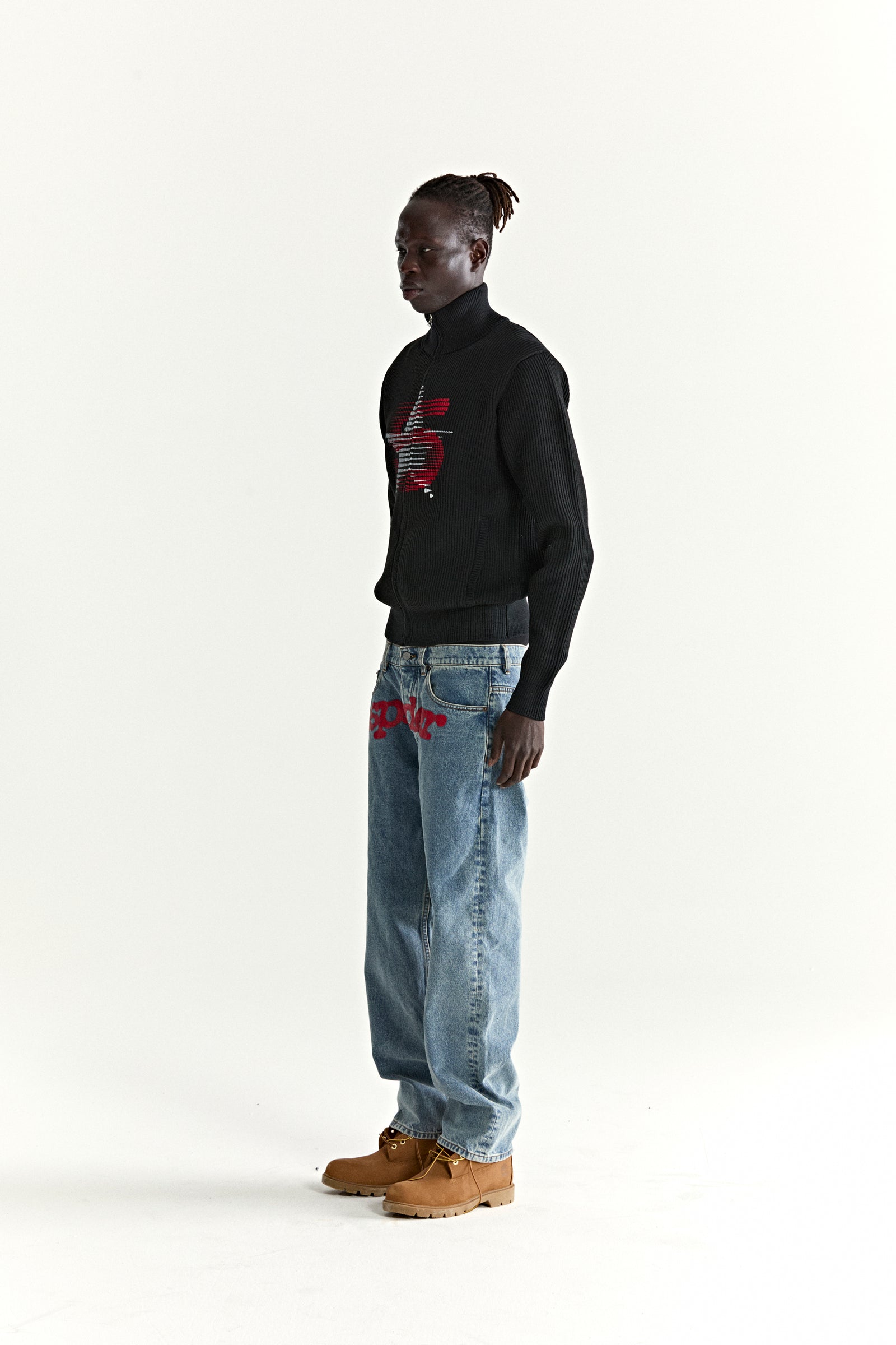 Black ribbed wool/cotton blend zip sweater with red graphic, worn by a man in blue jeans.