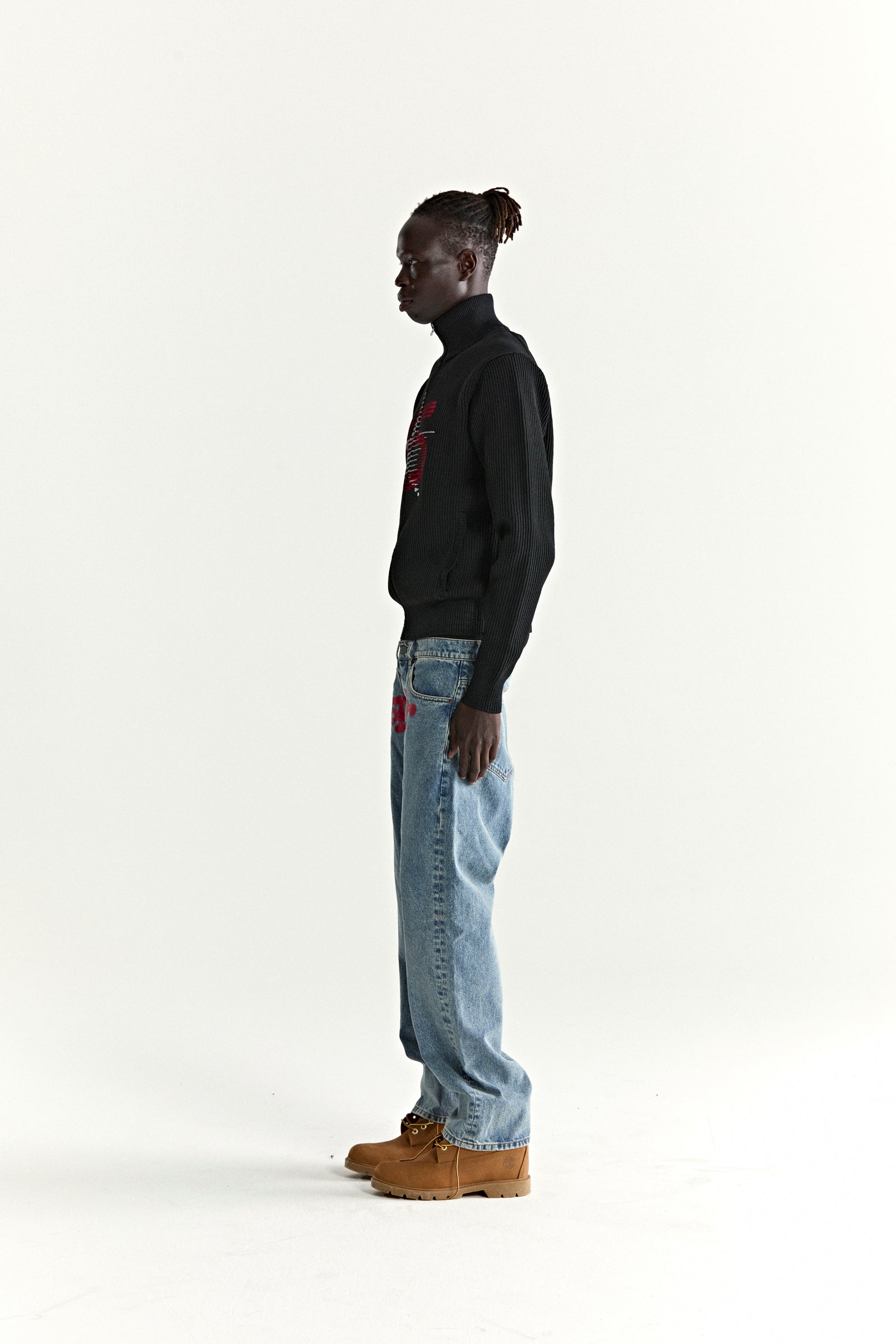 Black ribbed wool/cotton zip sweater with stand collar and red chest graphic, worn by a man.