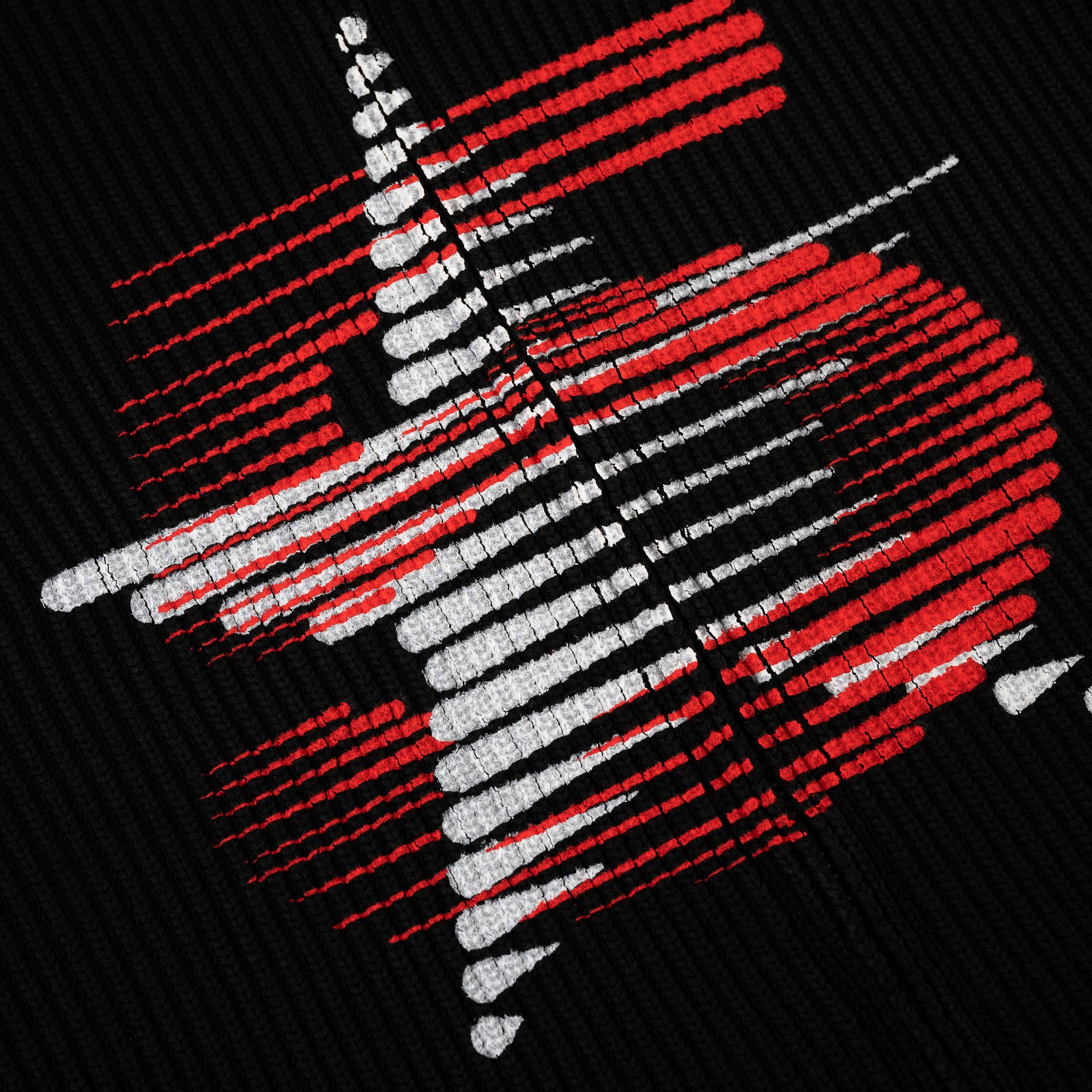 Black rib knit sweater with a red and white abstract graphic print at the chest.