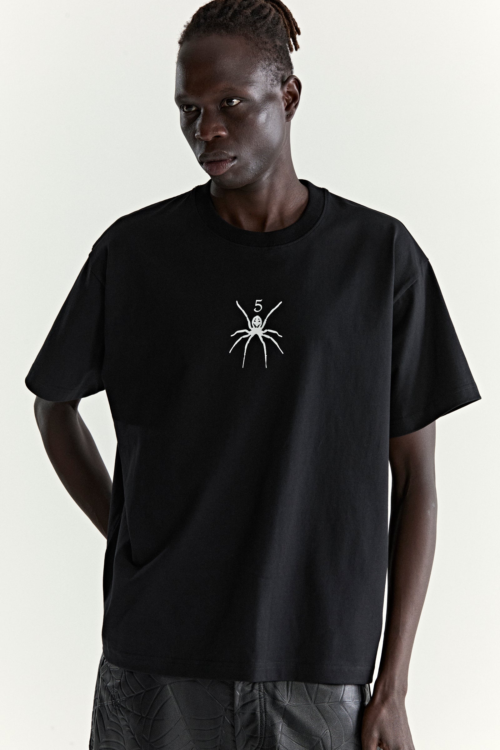 Black 100% cotton standard fit TM TEE with white spider graphic print on front, worn by a model.