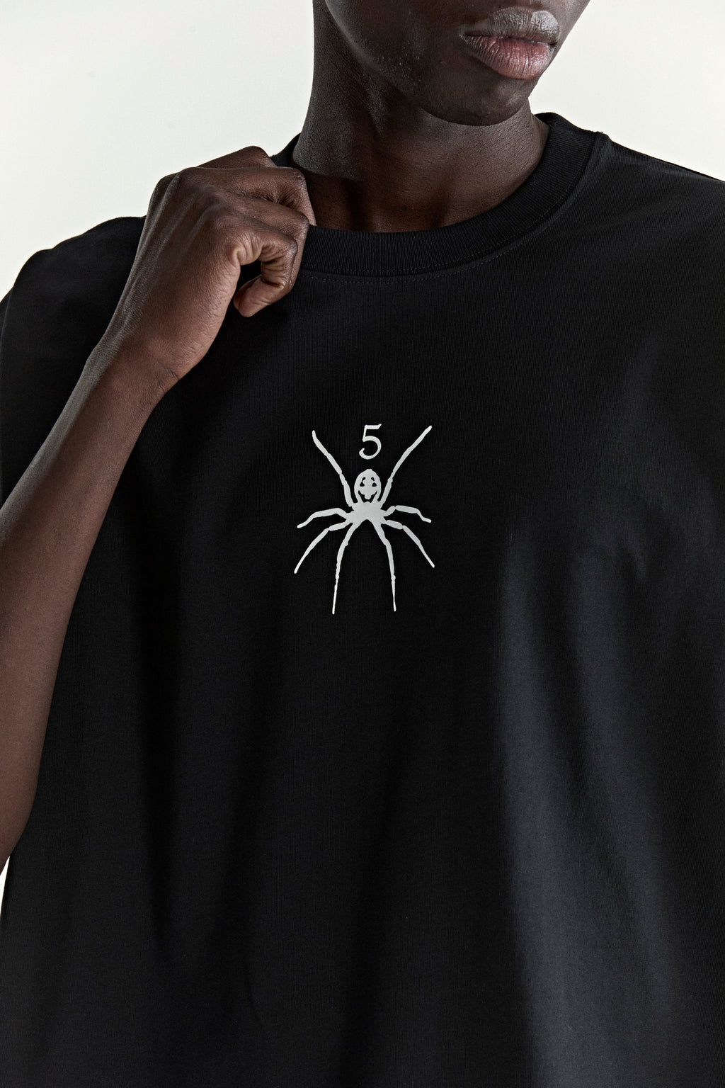 Black 100% cotton TM TEE with a white spider and "5" graphic print on the front.