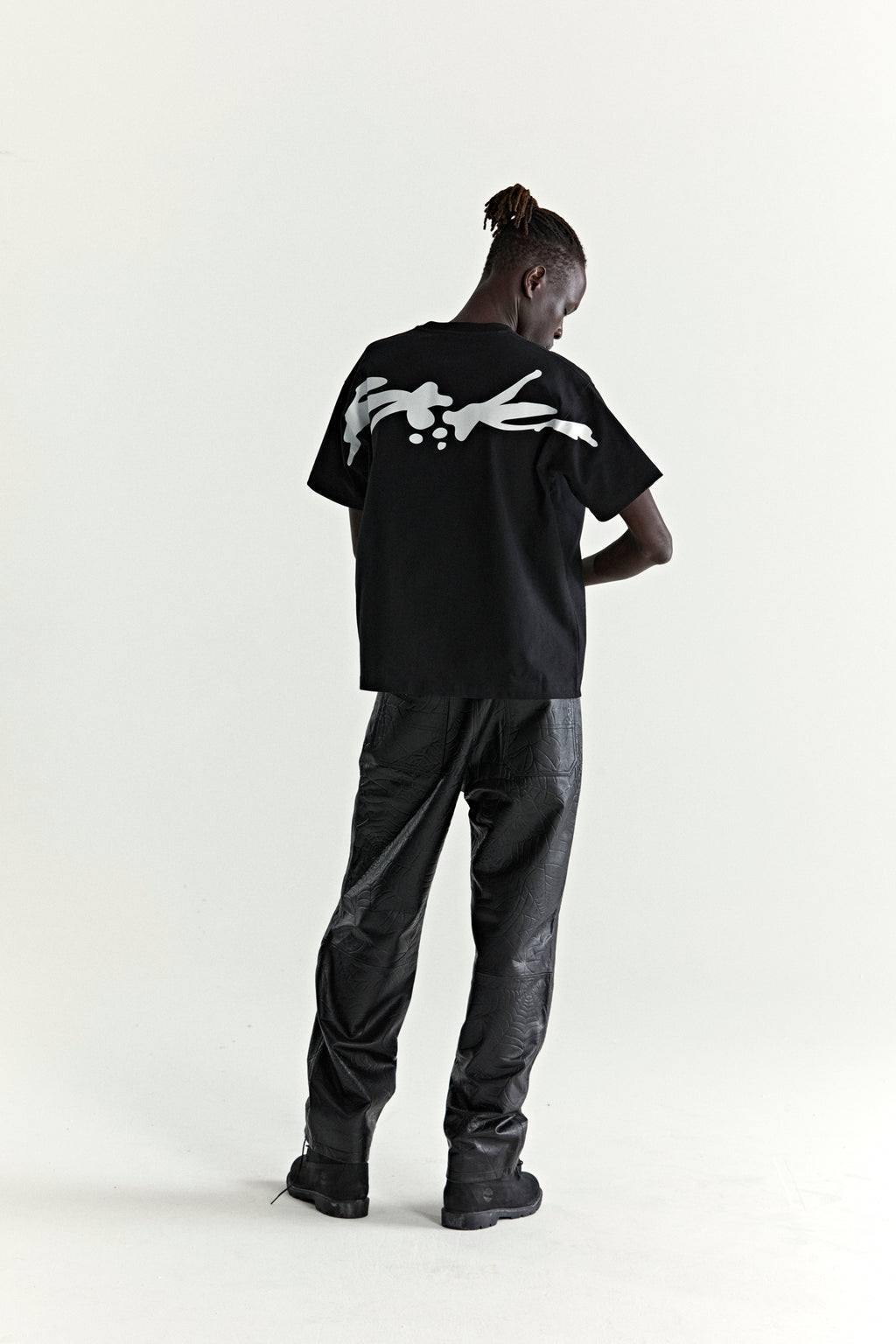 Black 100% cotton TM TEE with white graphic print on back, worn by a model.