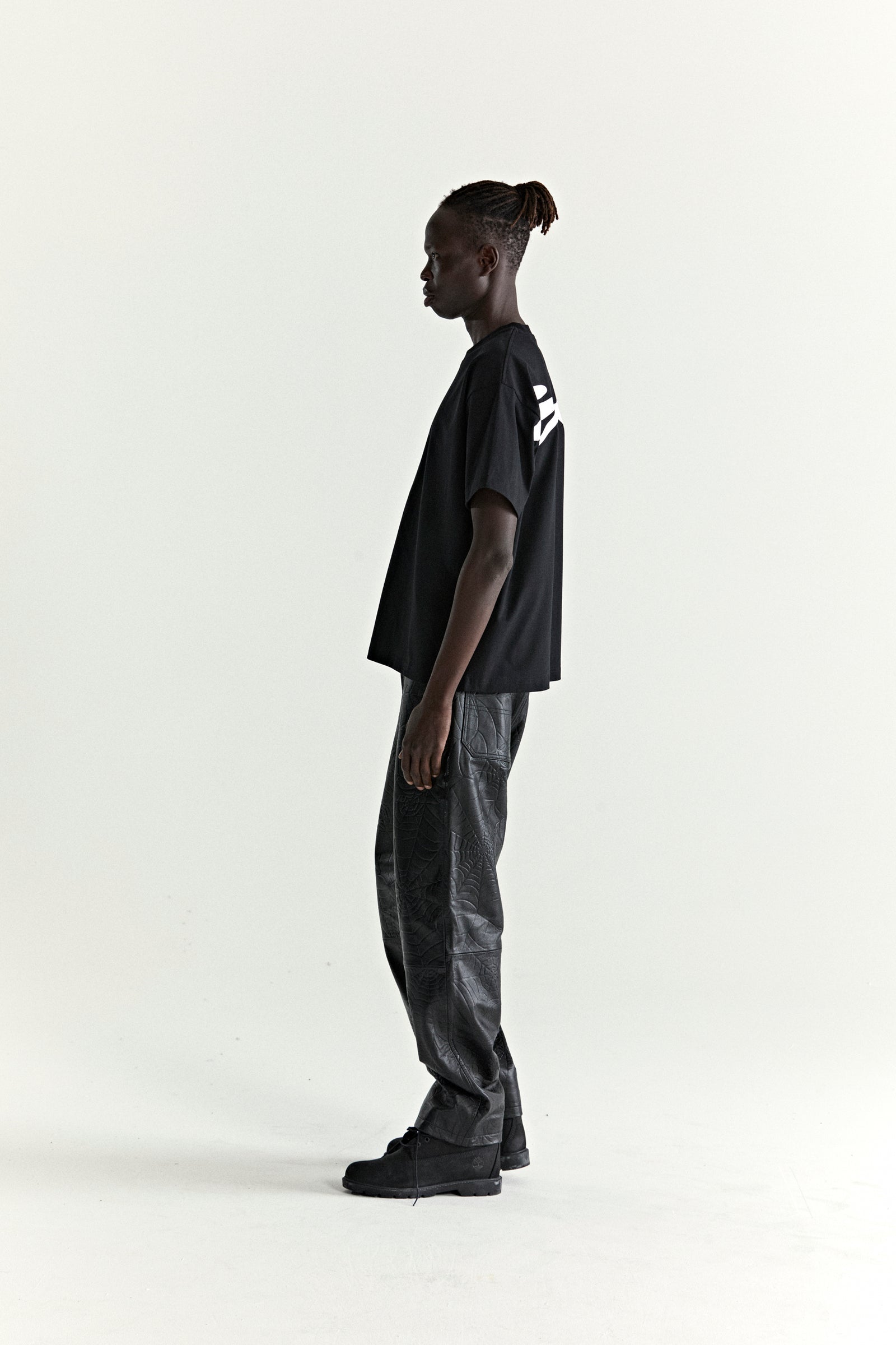 Black 100% cotton TM Tee with white graphic print on back, worn by a model in profile.