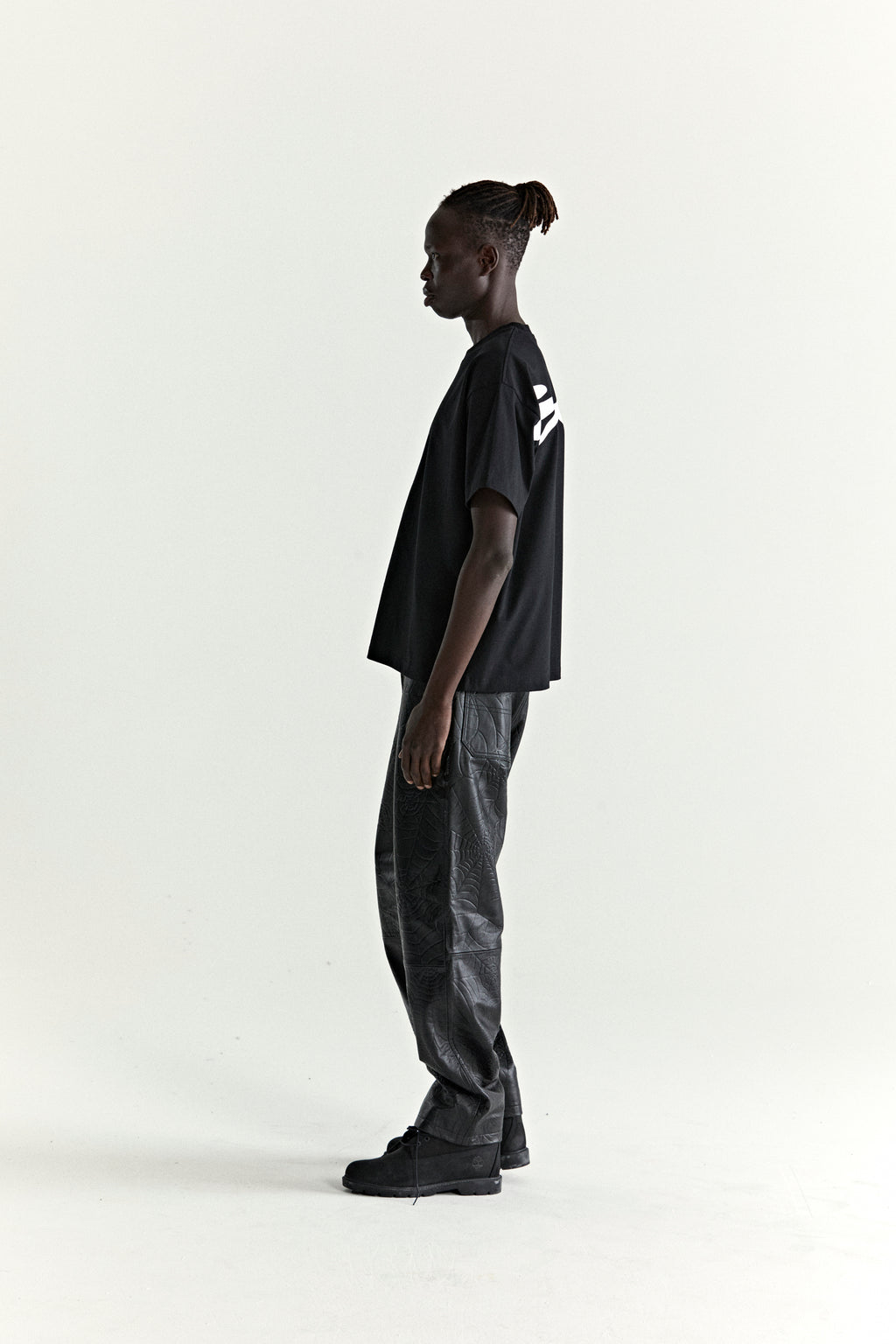 Black 100% cotton TM Tee with white graphic print on back, worn by a model in profile.