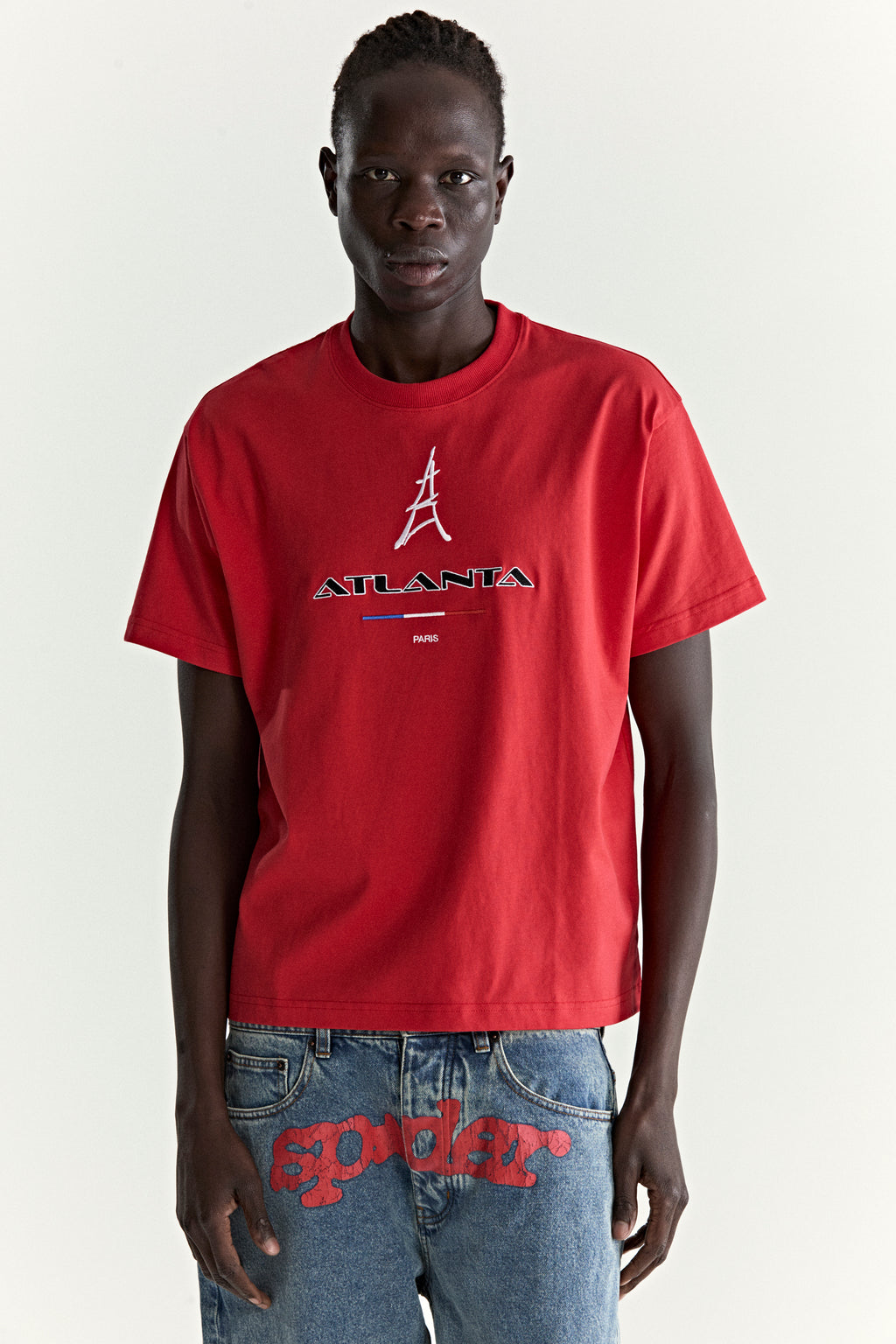 Man in red cotton ARAIGNÉE TEE with embroidered Atlanta Paris graphic and Eiffel Tower design.