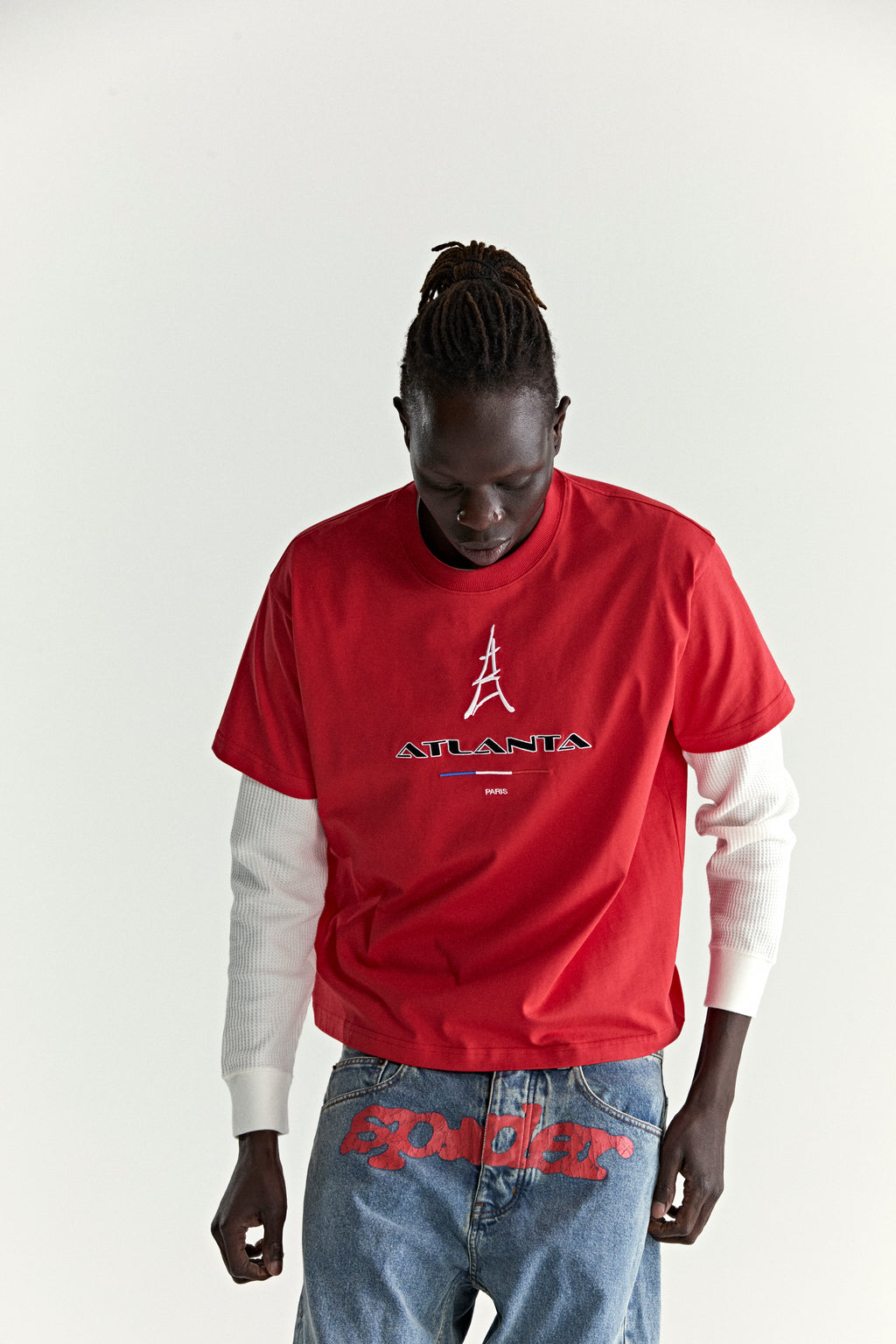 Red cotton tee with embroidered Eiffel Tower and "ATLANTA PARIS" graphic, worn by a person.
