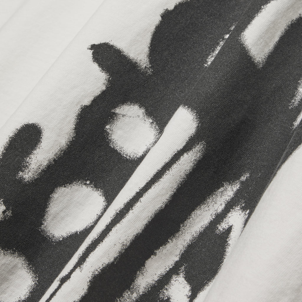 Close-up of a white cotton SP5 5LUMINUM TEE with a bold black graphic print.