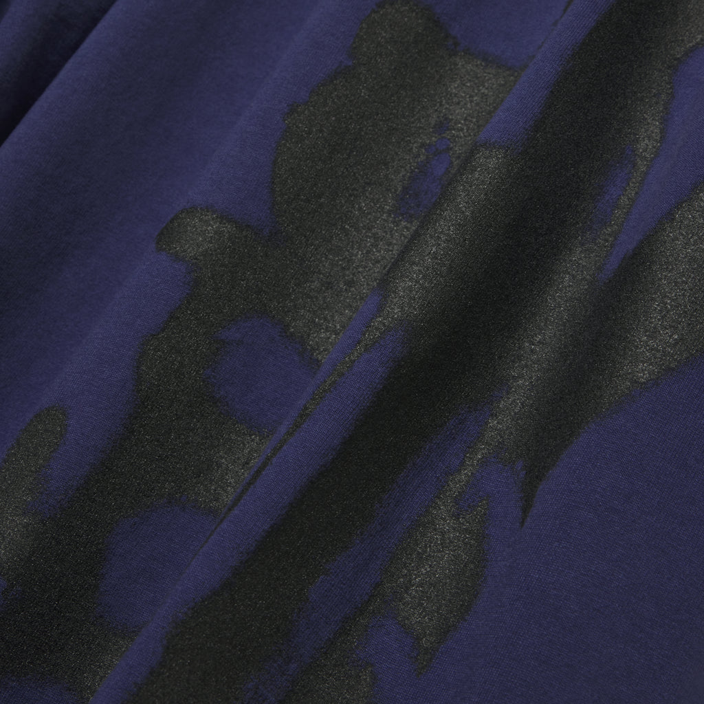 Close-up of a navy blue 100% cotton tee with a large, abstract black graphic print.