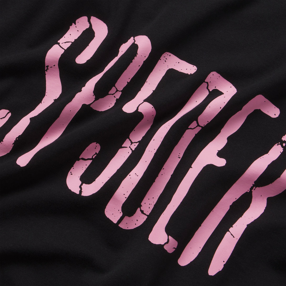 Black 100% cotton tee featuring a pink graphic print with a distressed, cracked texture design.