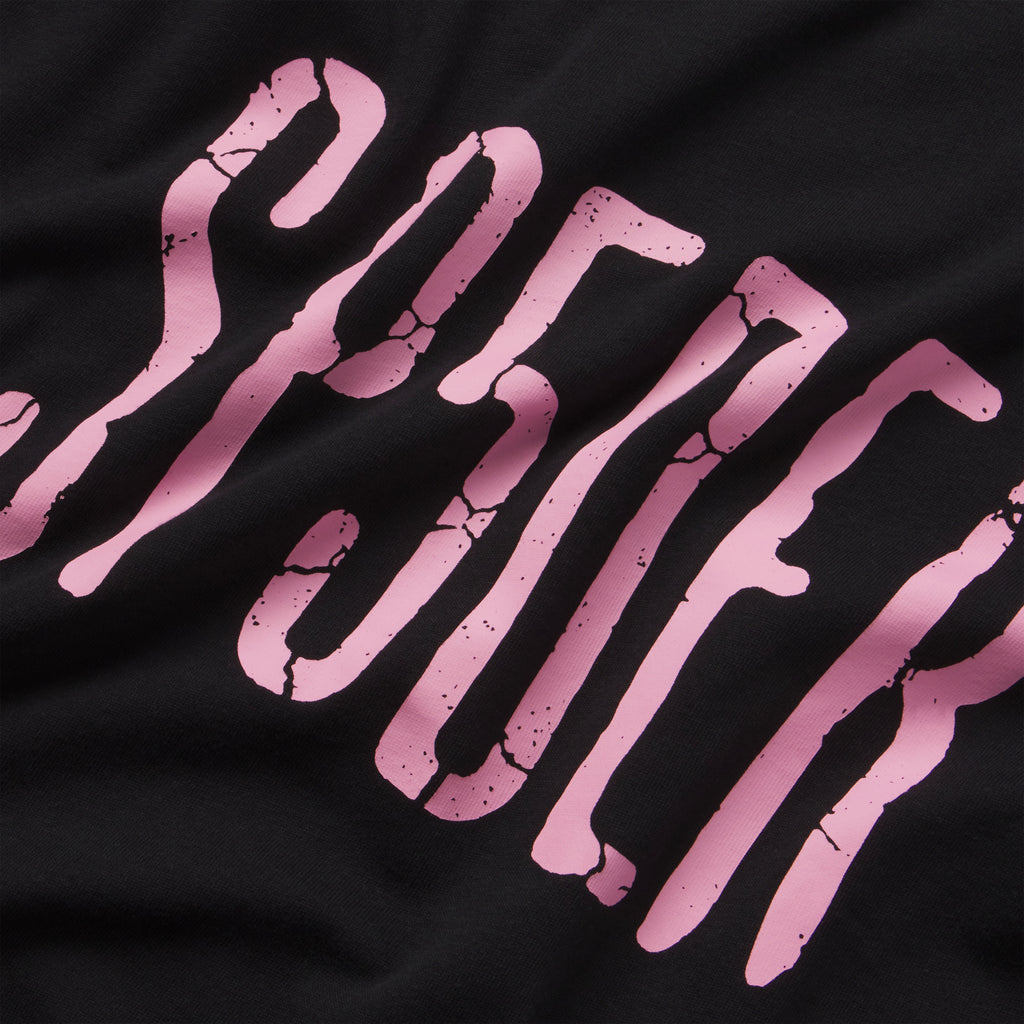 Black 100% cotton tee featuring a pink graphic print with a distressed, cracked texture design.