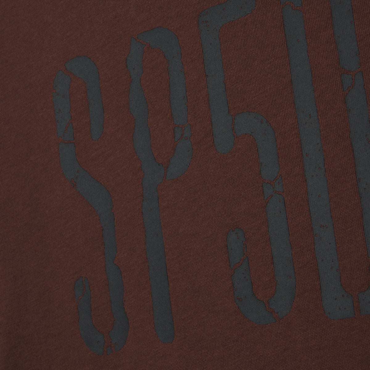 Brown 100% cotton tee featuring a dark grey graphic print with a distressed, cracked texture design.
