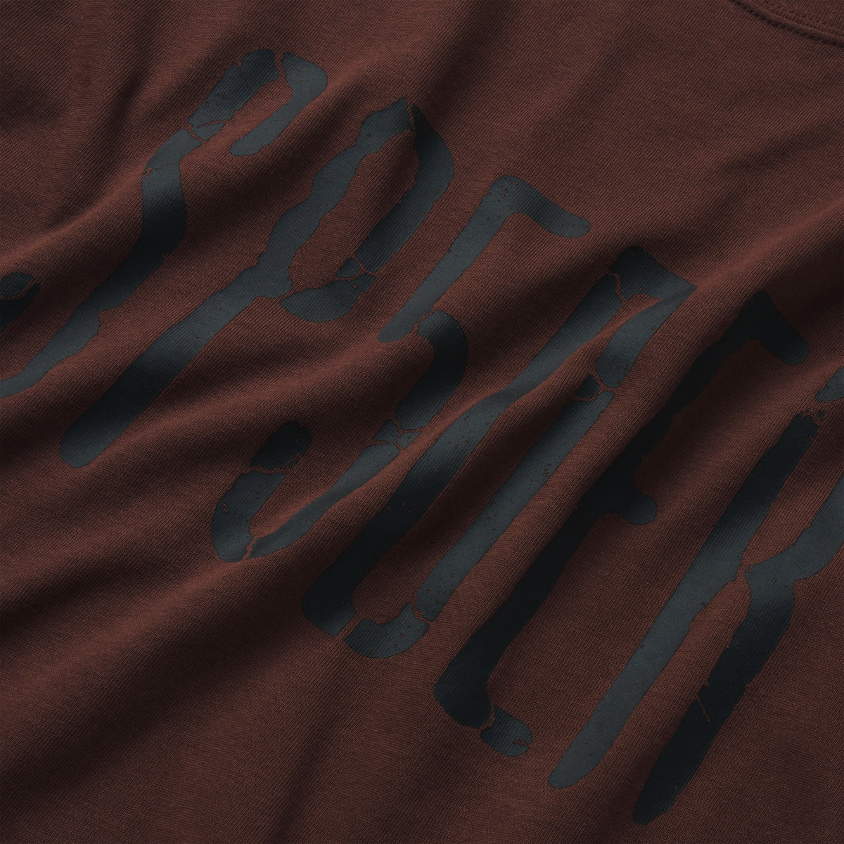 Brown 100% cotton t-shirt featuring a black graphic print with a distressed, cracked texture design.
