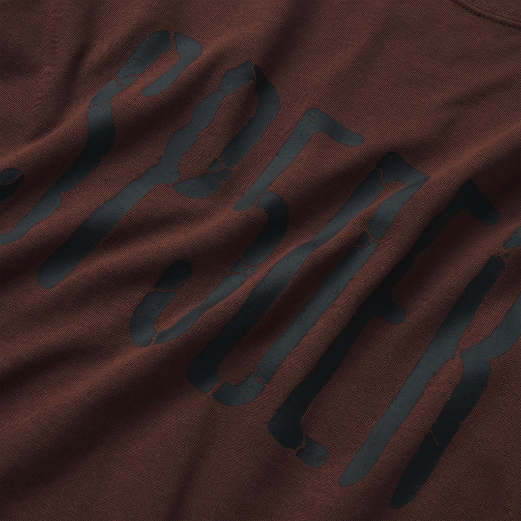 Brown 100% cotton t-shirt featuring a black graphic print with a distressed, cracked texture design.