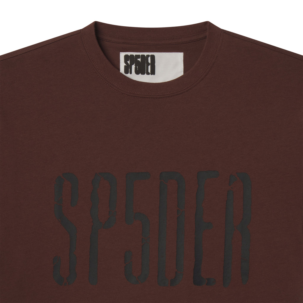 Brown 100% cotton standard fit tee featuring a black cracked graphic print logo on the front and an inner neck label.