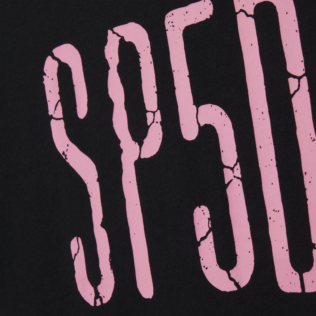 Black 100% cotton tee featuring a pink graphic print with a distressed, cracked texture design.