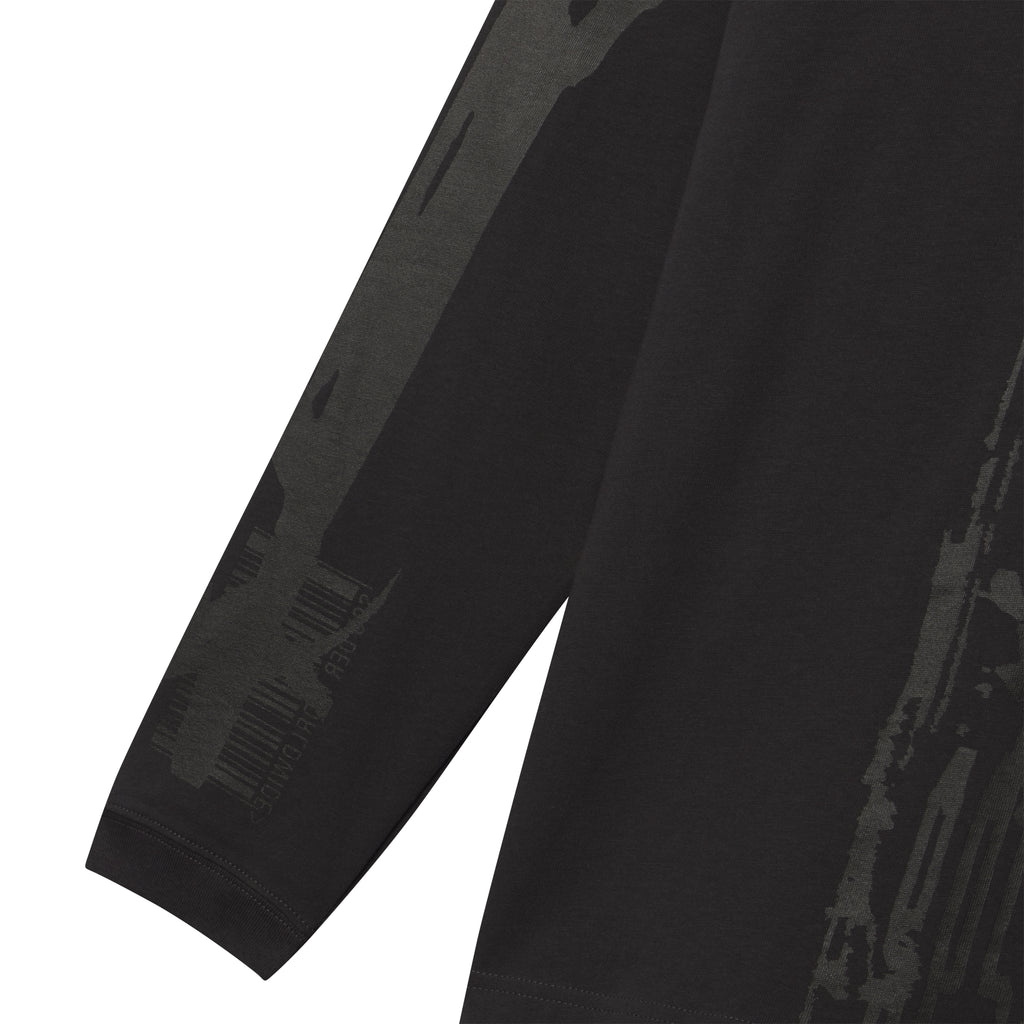 Black 100% cotton long sleeve tee featuring a dark grey fragmented graphic print on the sleeve and body.