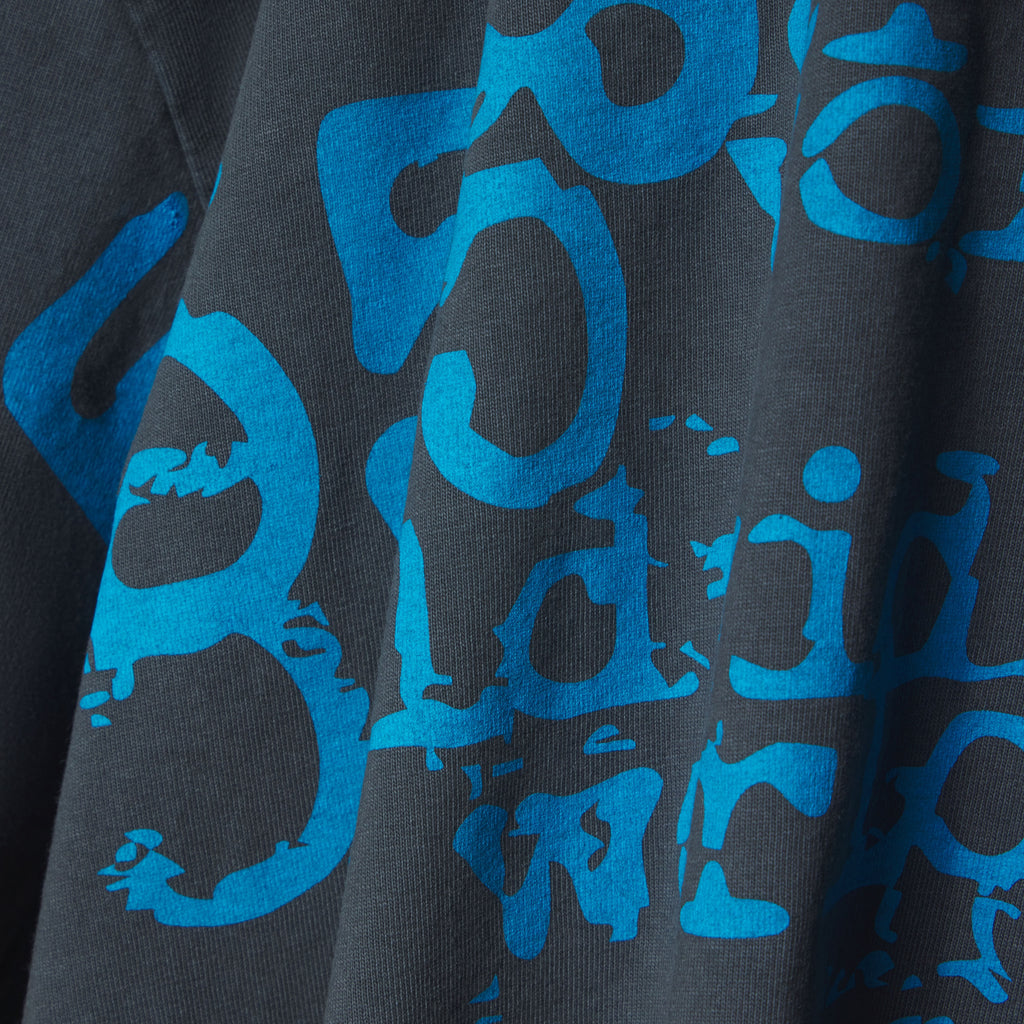 Close-up of a dark grey cotton tee with a distressed blue graphic print.