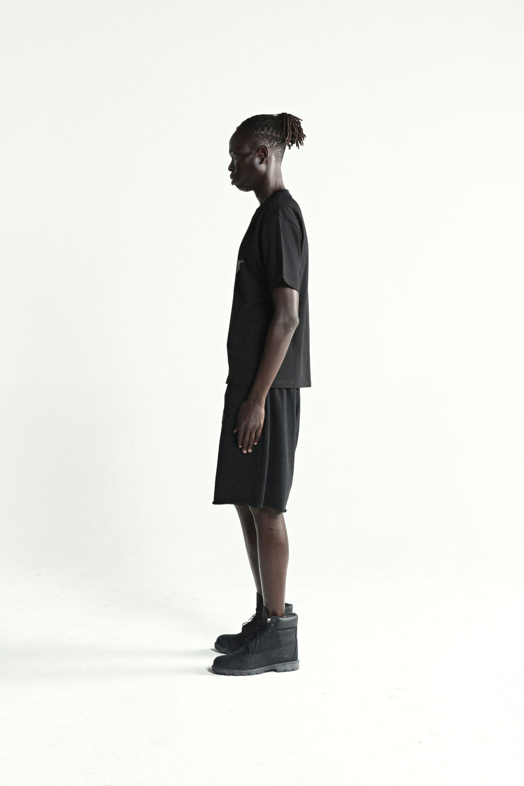Black 100% cotton tee with rhinestone 5-star design, standard fit, worn by a model in profile.