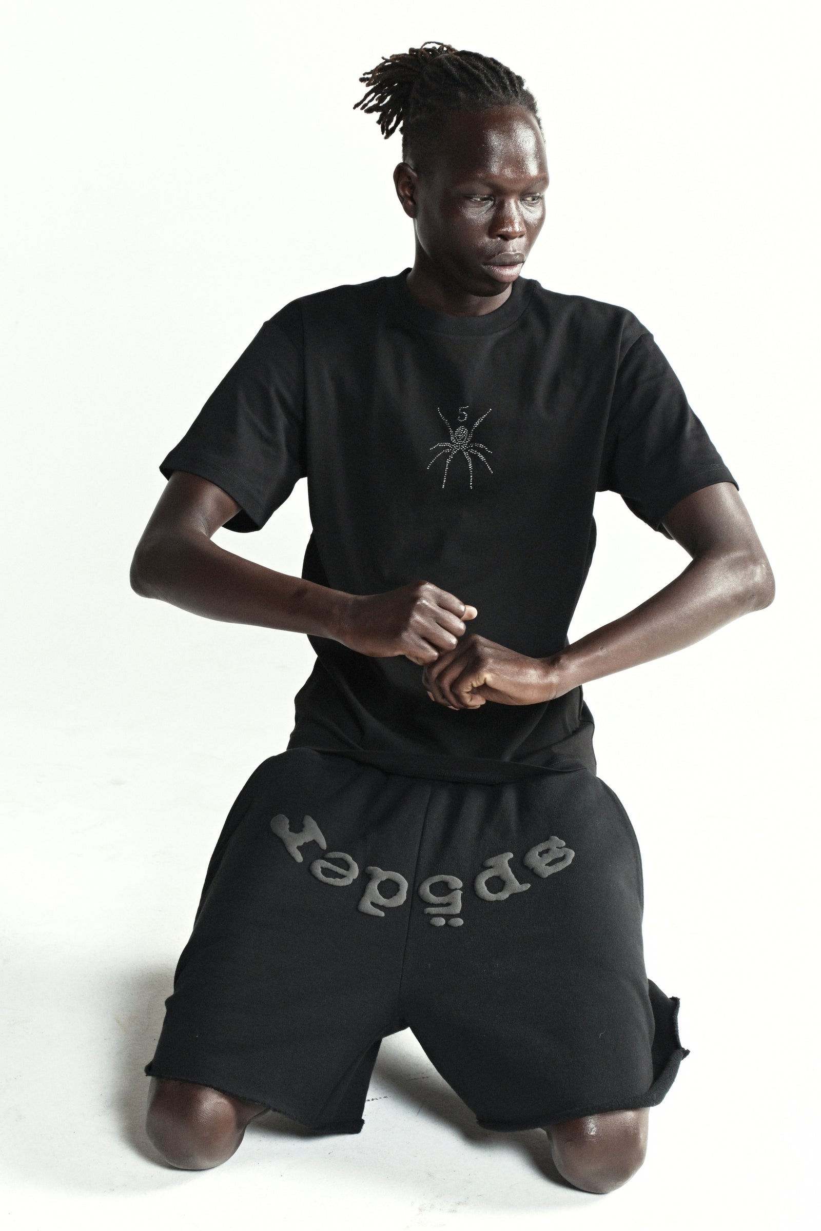 Black cotton tee with rhinestone spider graphic, paired with black shorts.
