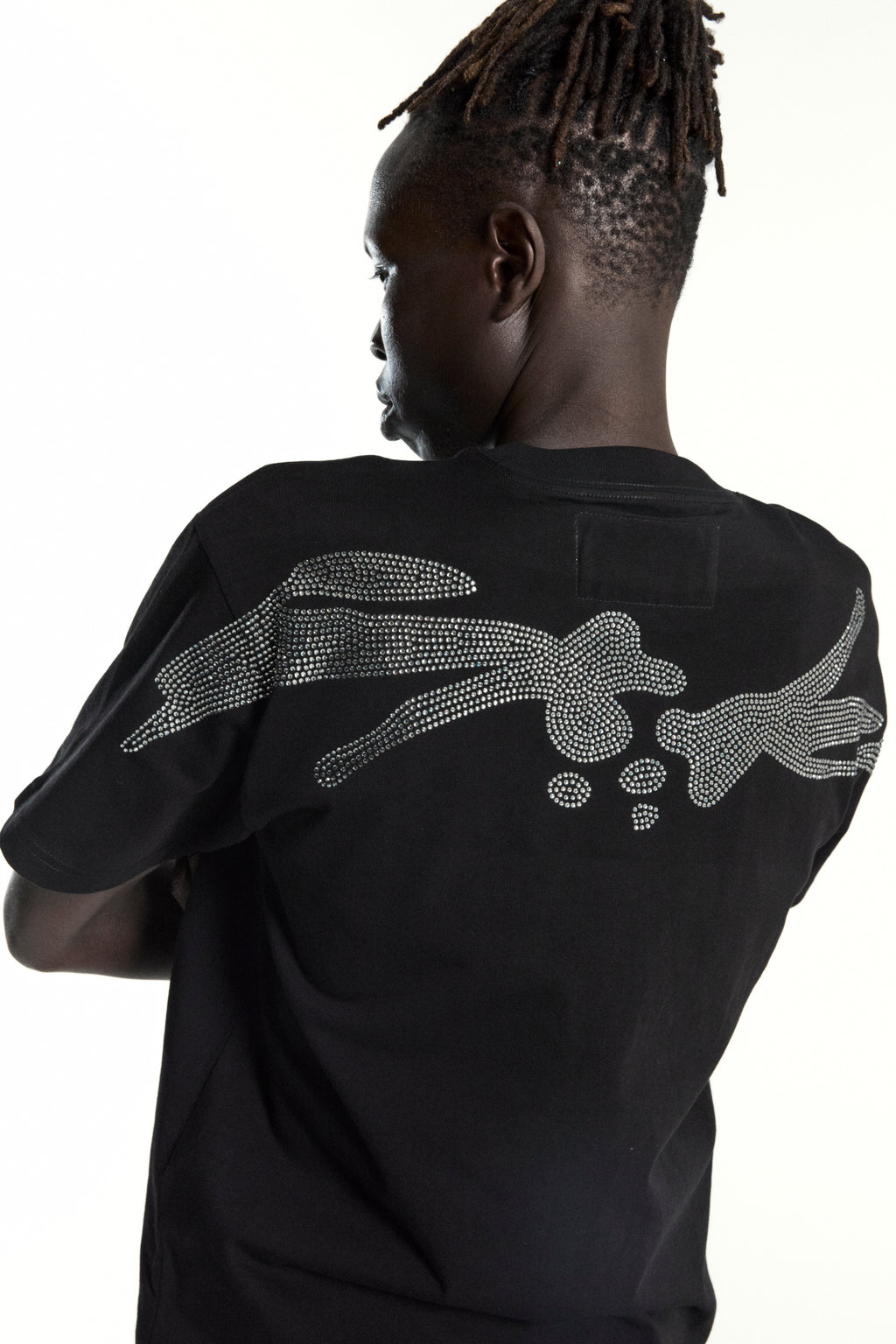 Black cotton tee with rhinestone embellished bone graphic on the back, worn by a person with dreadlocks.