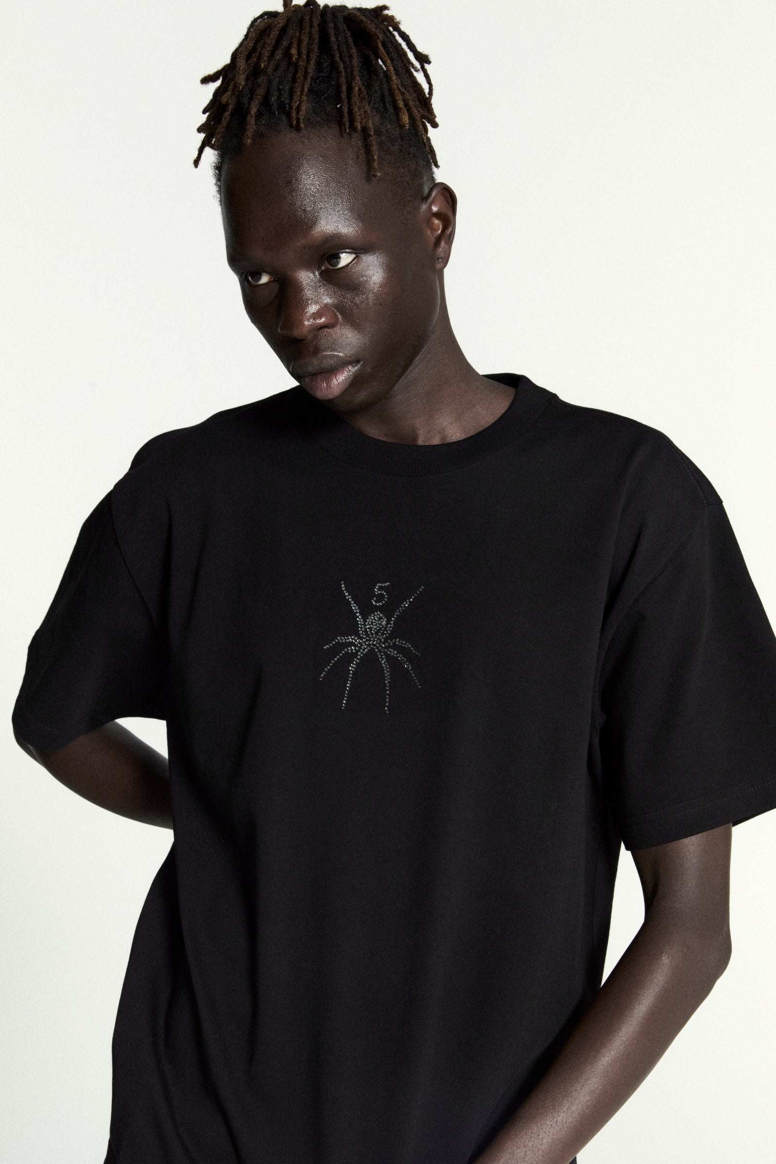 Black 100% cotton standard fit tee with a rhinestone spider graphic on the front.