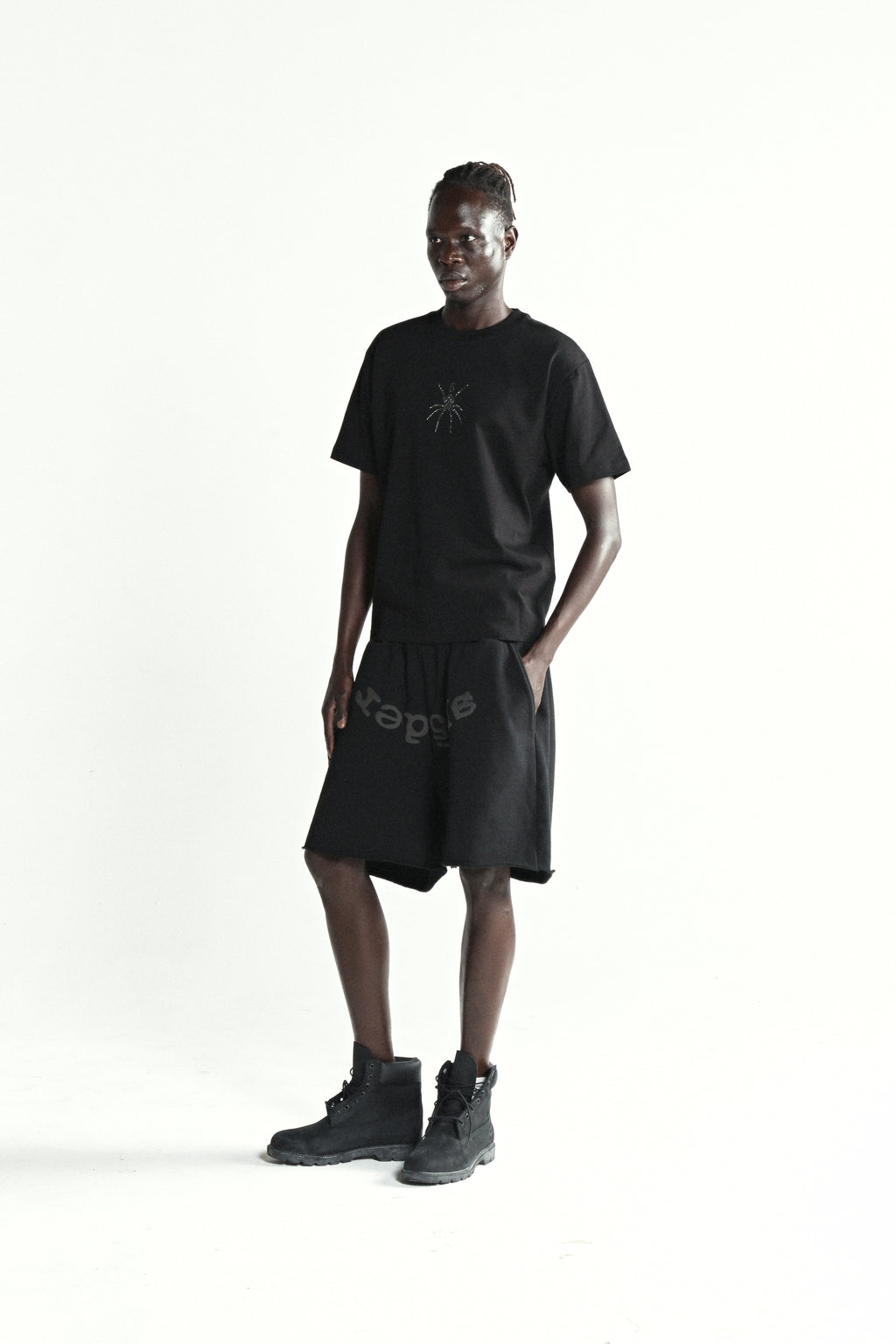 Black cotton tee with rhinestone graphic, black shorts, and black boots on a male model.