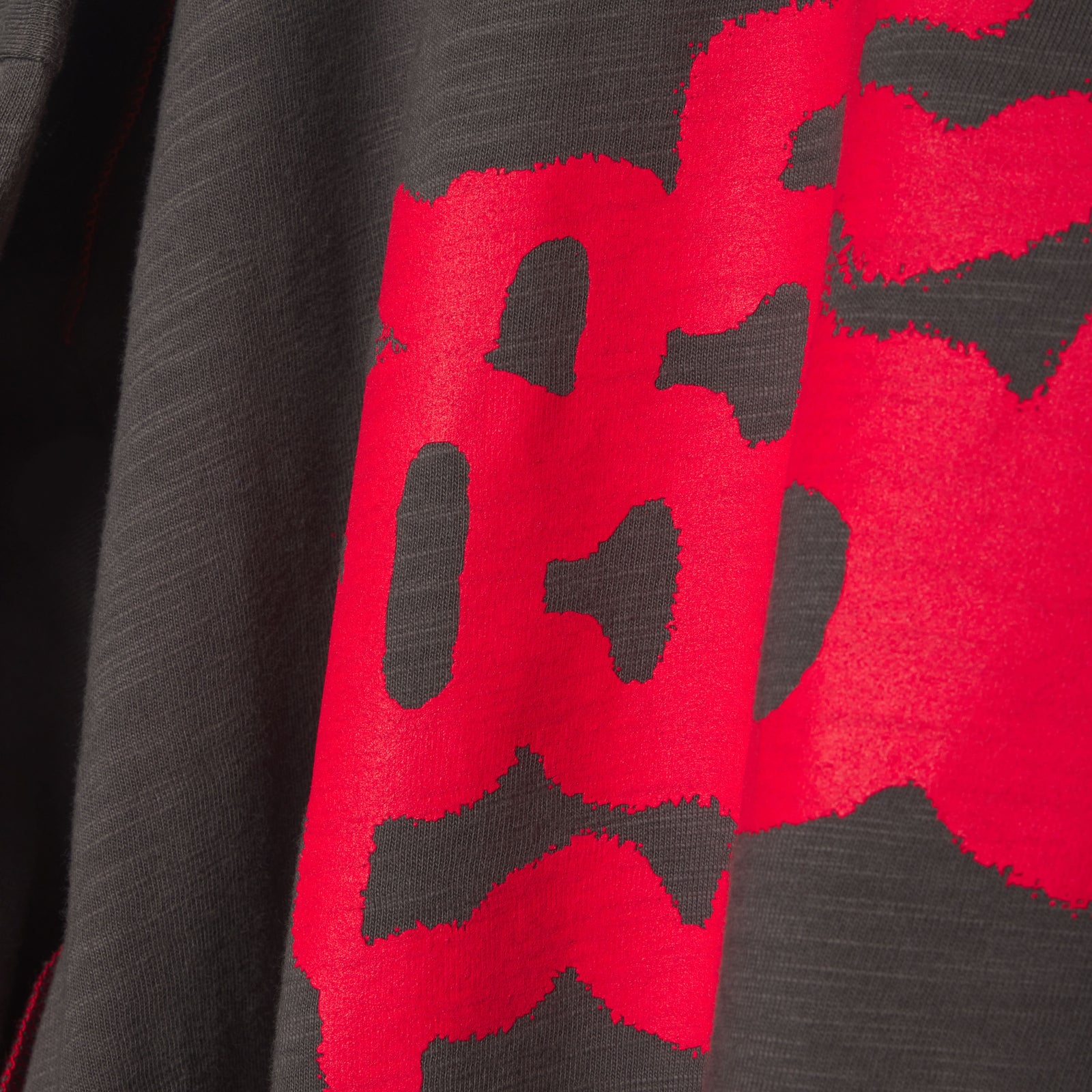 Close-up of a dark grey slub jersey tee with a bold red graphic print.