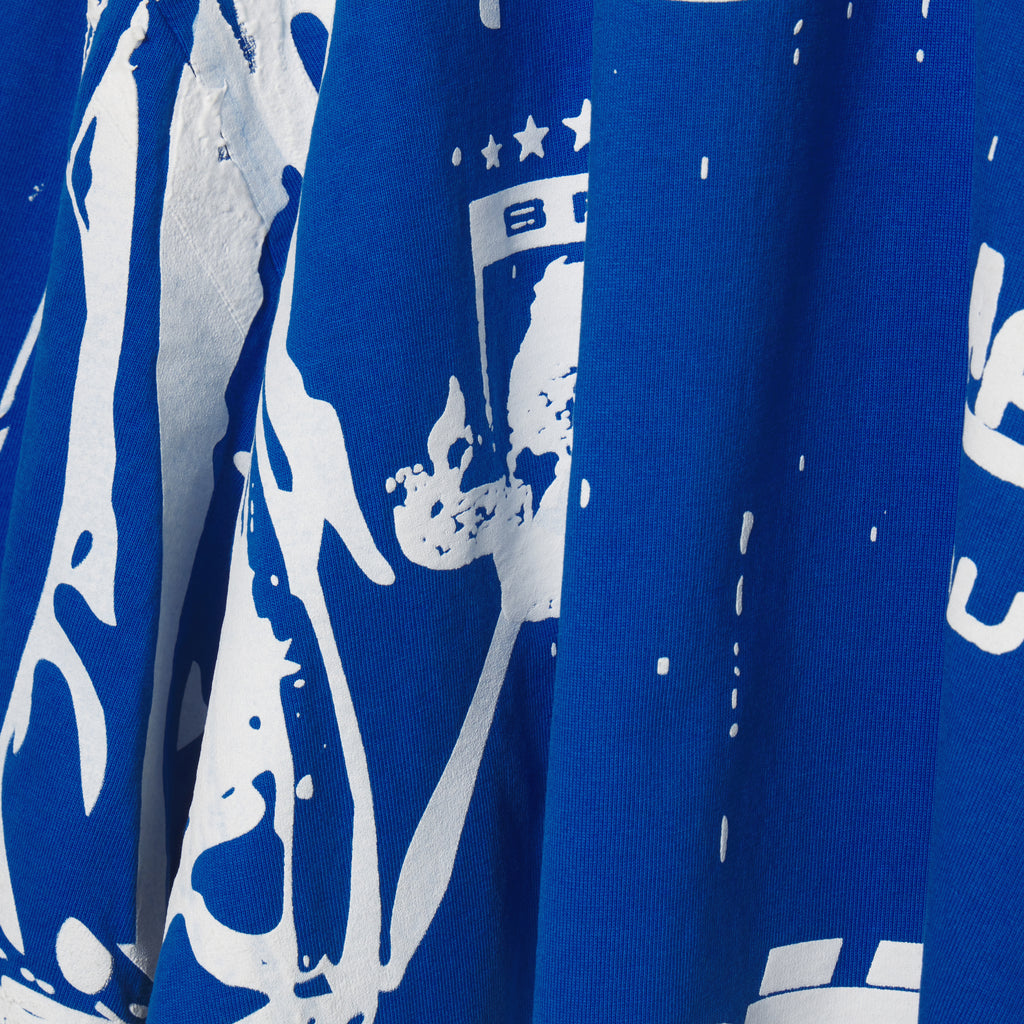 Close-up of a blue 100% cotton tee with a white trompe l'œil graphic print.