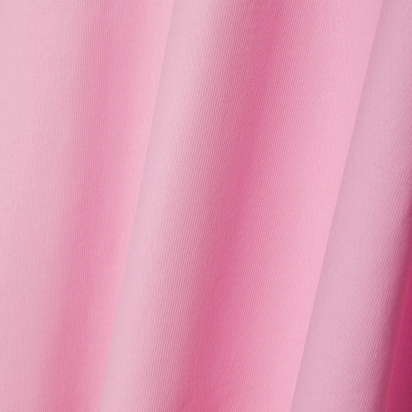 Close-up of a pink 100% cotton tee with a subtle fabric texture and soft folds.