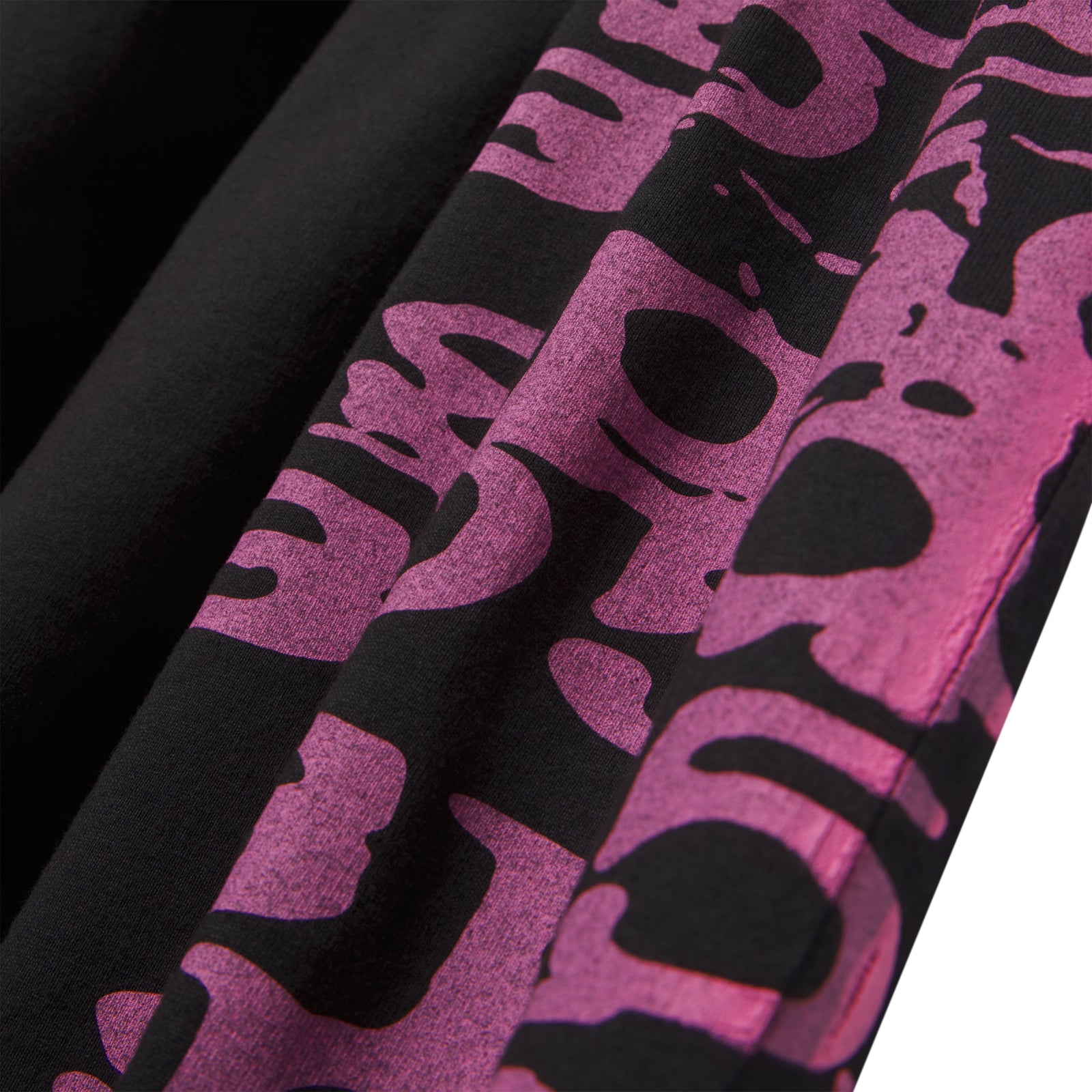 Black 100% cotton STACKED TEE with a vibrant pink wraparound graphic print, showing fabric folds.