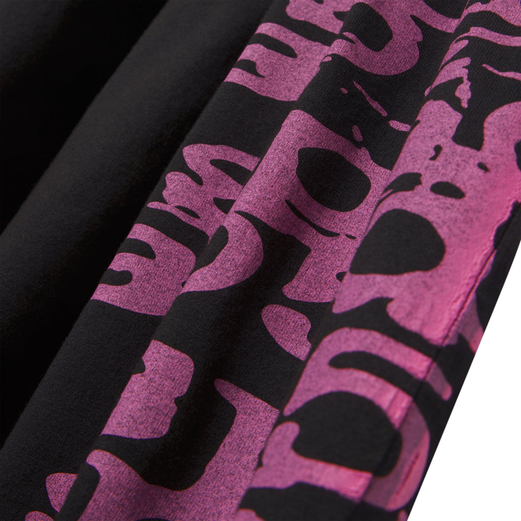 Black 100% cotton STACKED TEE with a vibrant pink wraparound graphic print, showing fabric folds.