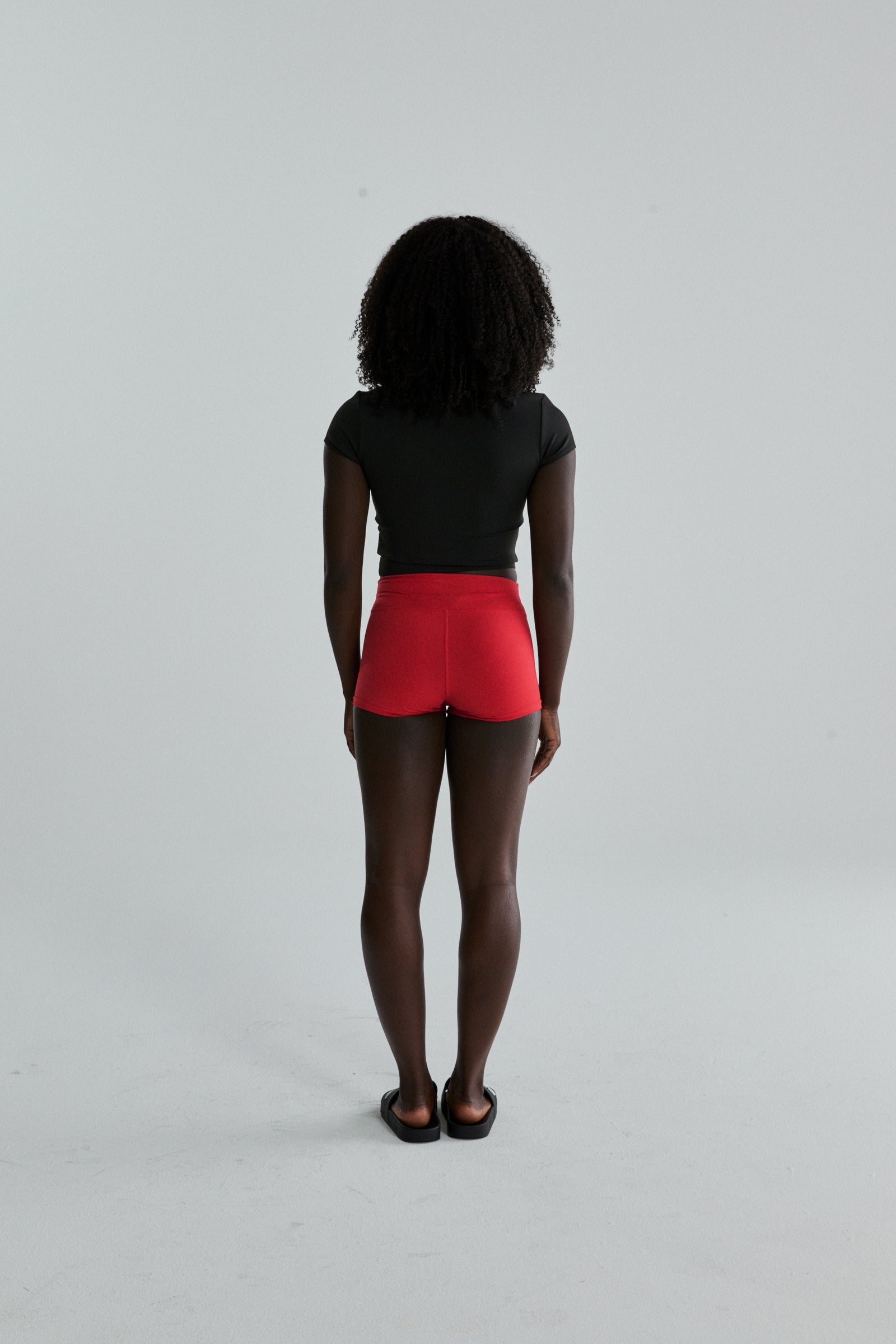 Woman from behind wearing red stretch cotton jersey SP5WOM TINY SHORT with elasticized waistband.