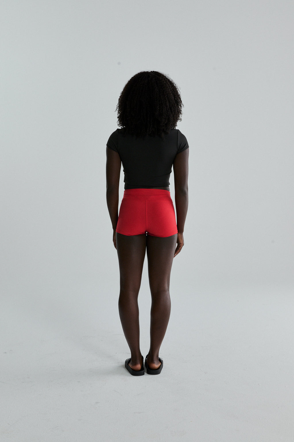 Woman from behind wearing red stretch cotton jersey SP5WOM TINY SHORT with elasticized waistband.