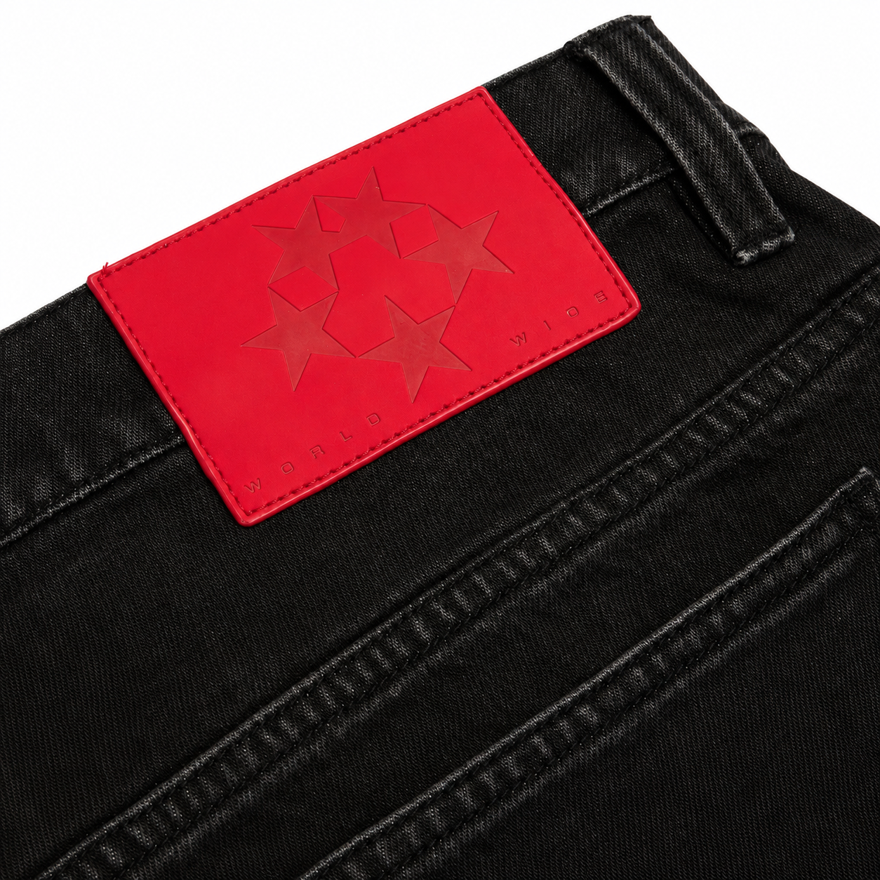 Black denim jeans featuring a red leather back patch with embossed star graphic design and World Wide branding.