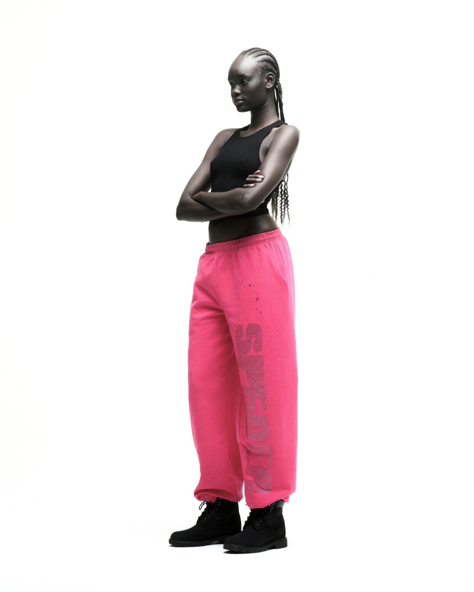 Model wearing hot pink cotton fleece sweatpants with rhinestone "SPORTY" embellishment and black boots.
