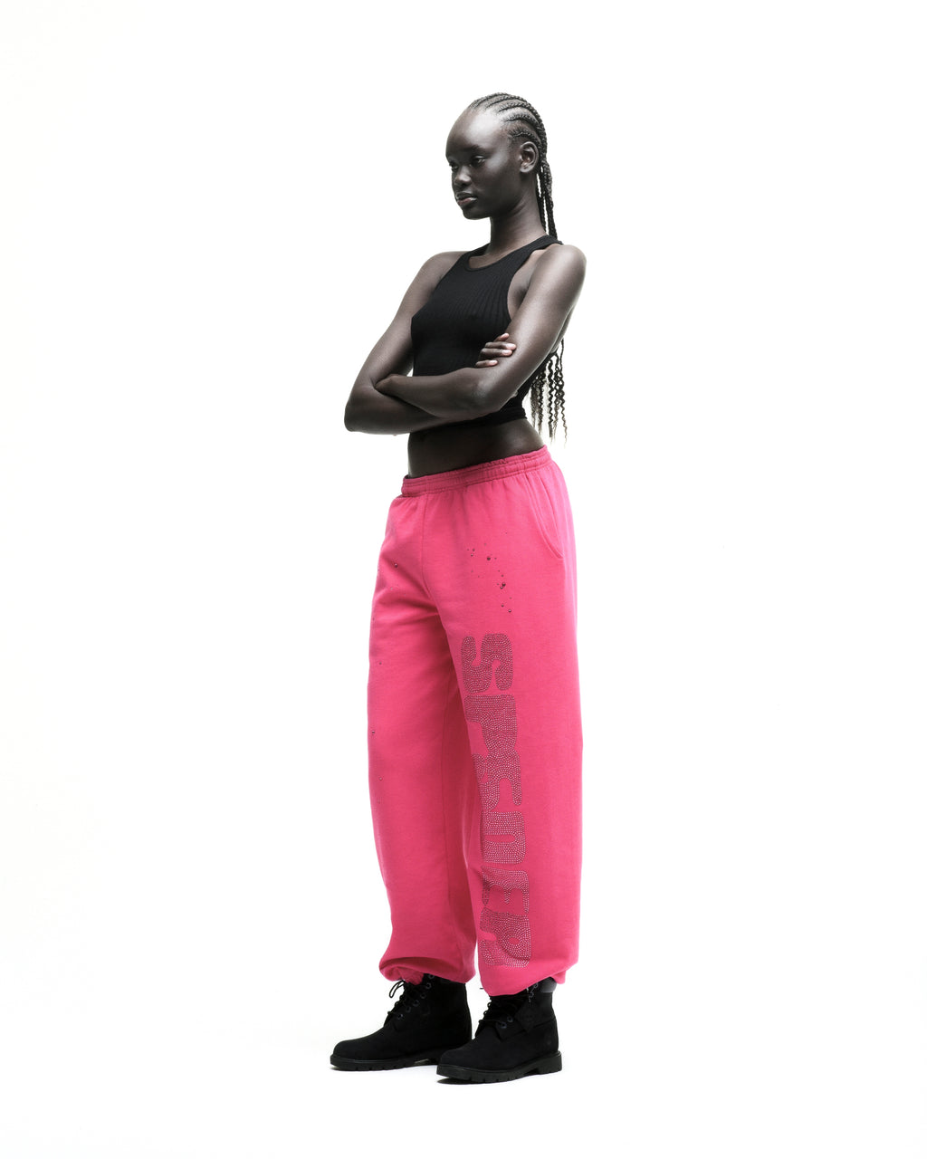 Model wearing hot pink cotton fleece sweatpants with rhinestone "SPORTY" embellishment and black boots.