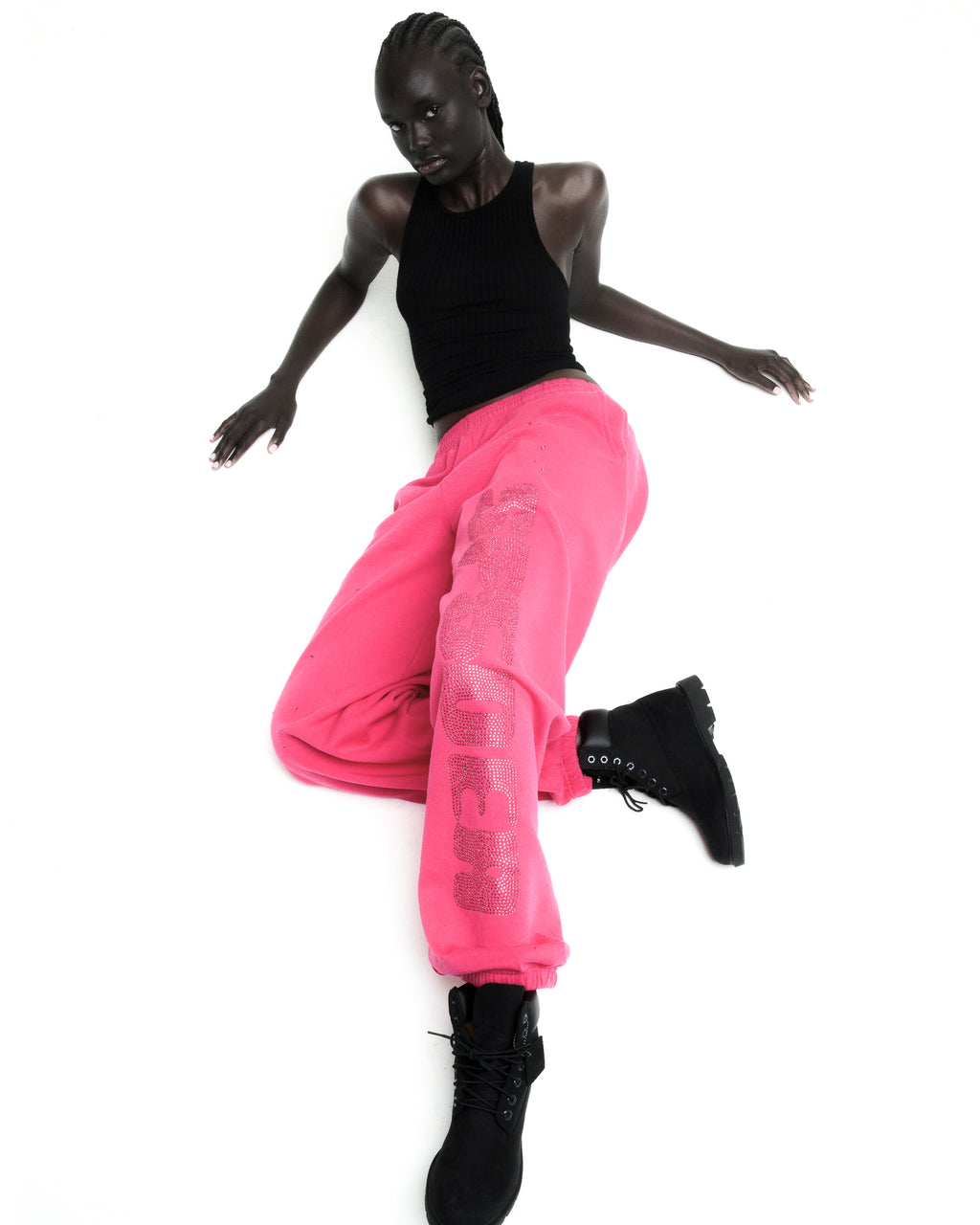 Model in pink rhinestone silk sweatpants with elasticized cuffs and waistband, paired with a black tank top and boots.